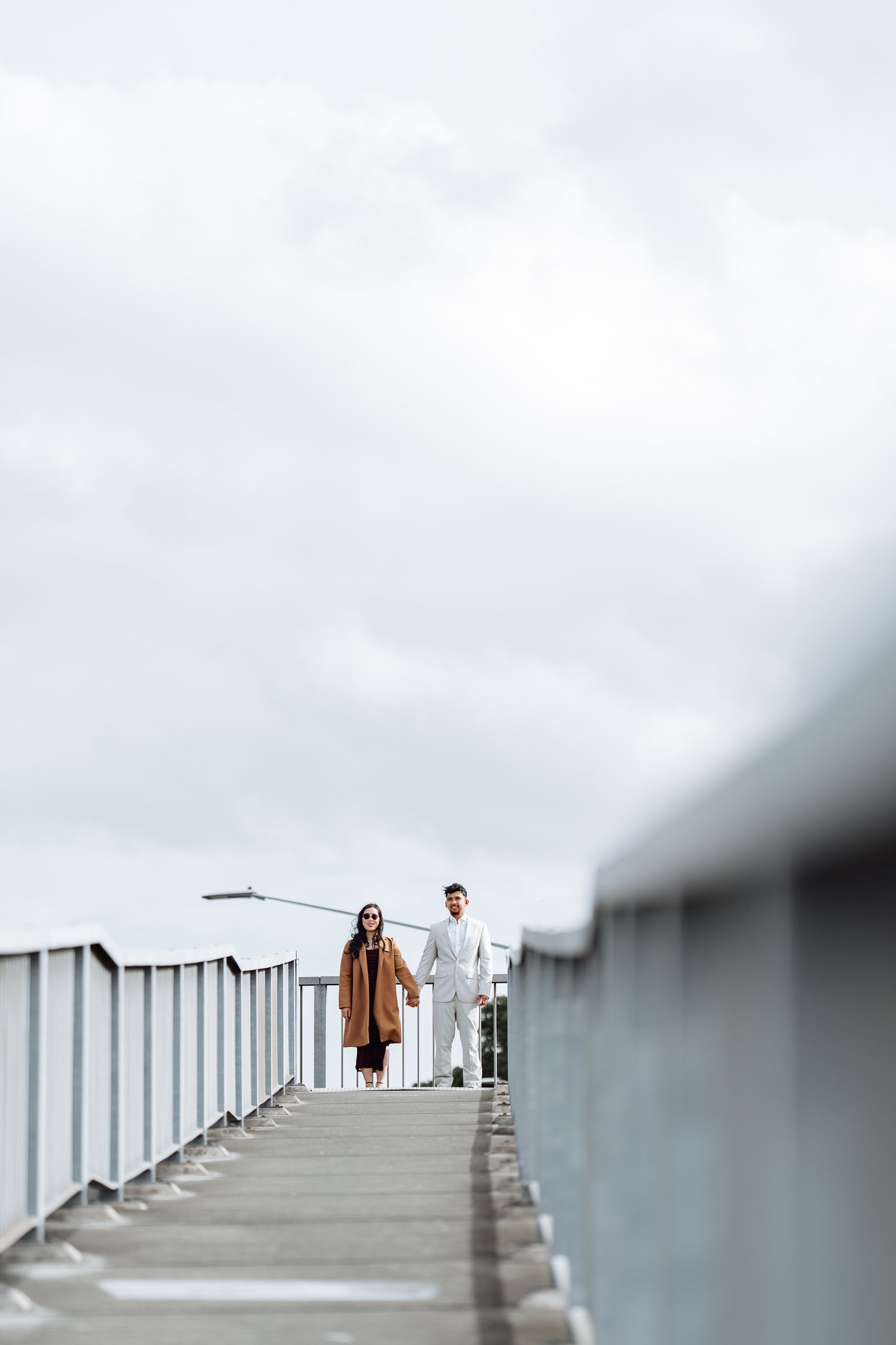 Couple strolling on an elevated walkway with white railings in minimalist architectural setting.