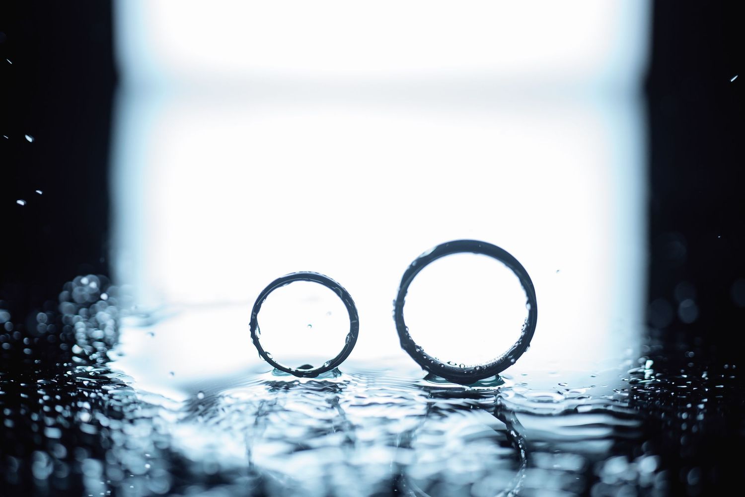 Wedding rings photographed in silhouette against bright backlight.