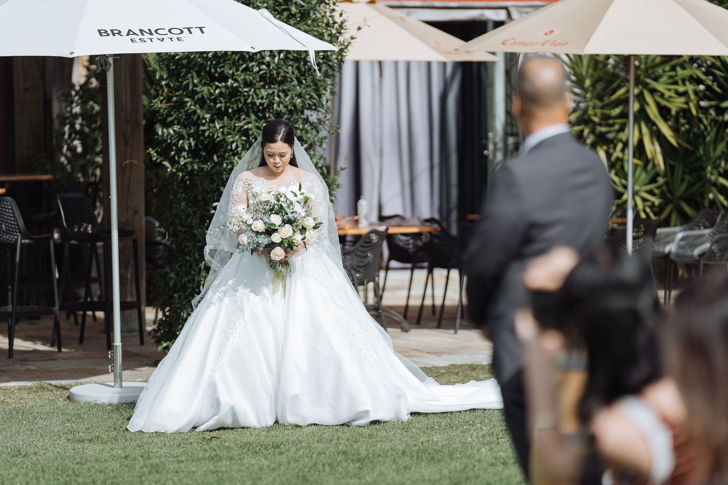 Outdoor wedding ceremony setup with white chairs and floral arrangements.