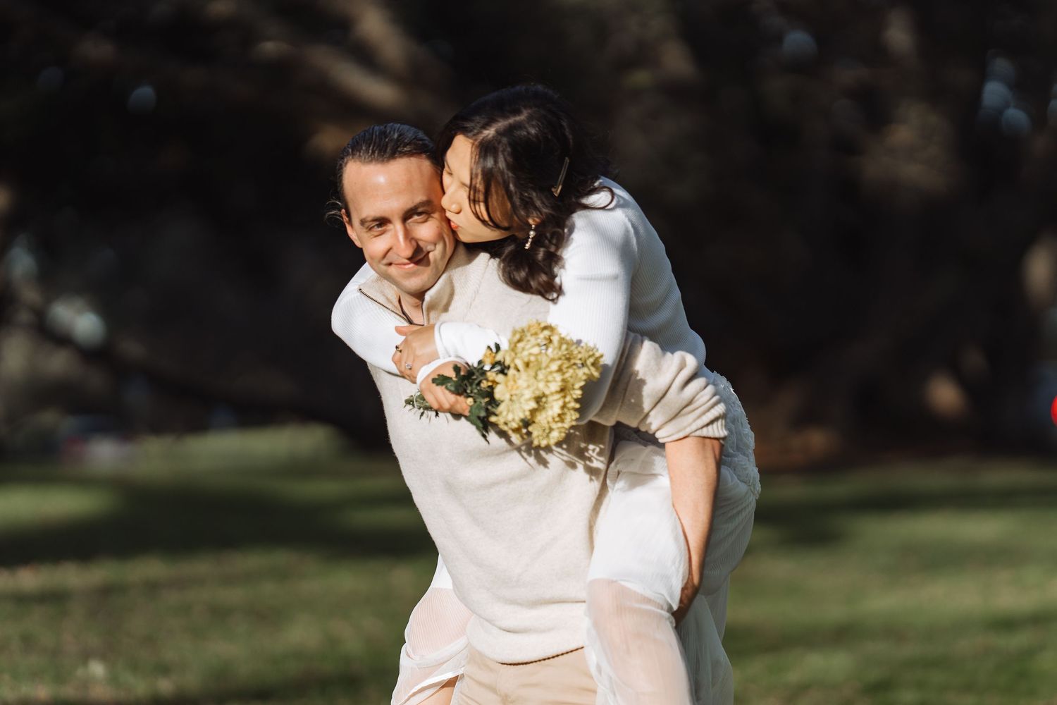 A couple shares playful moments during their outdoor photoshoot in a park.