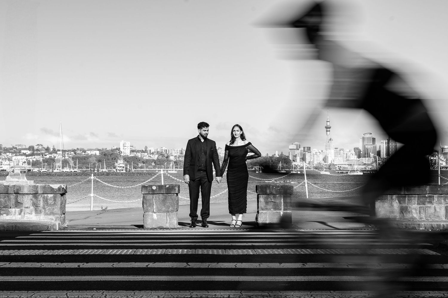 Black and white silhouettes of people walking along a waterfront path.