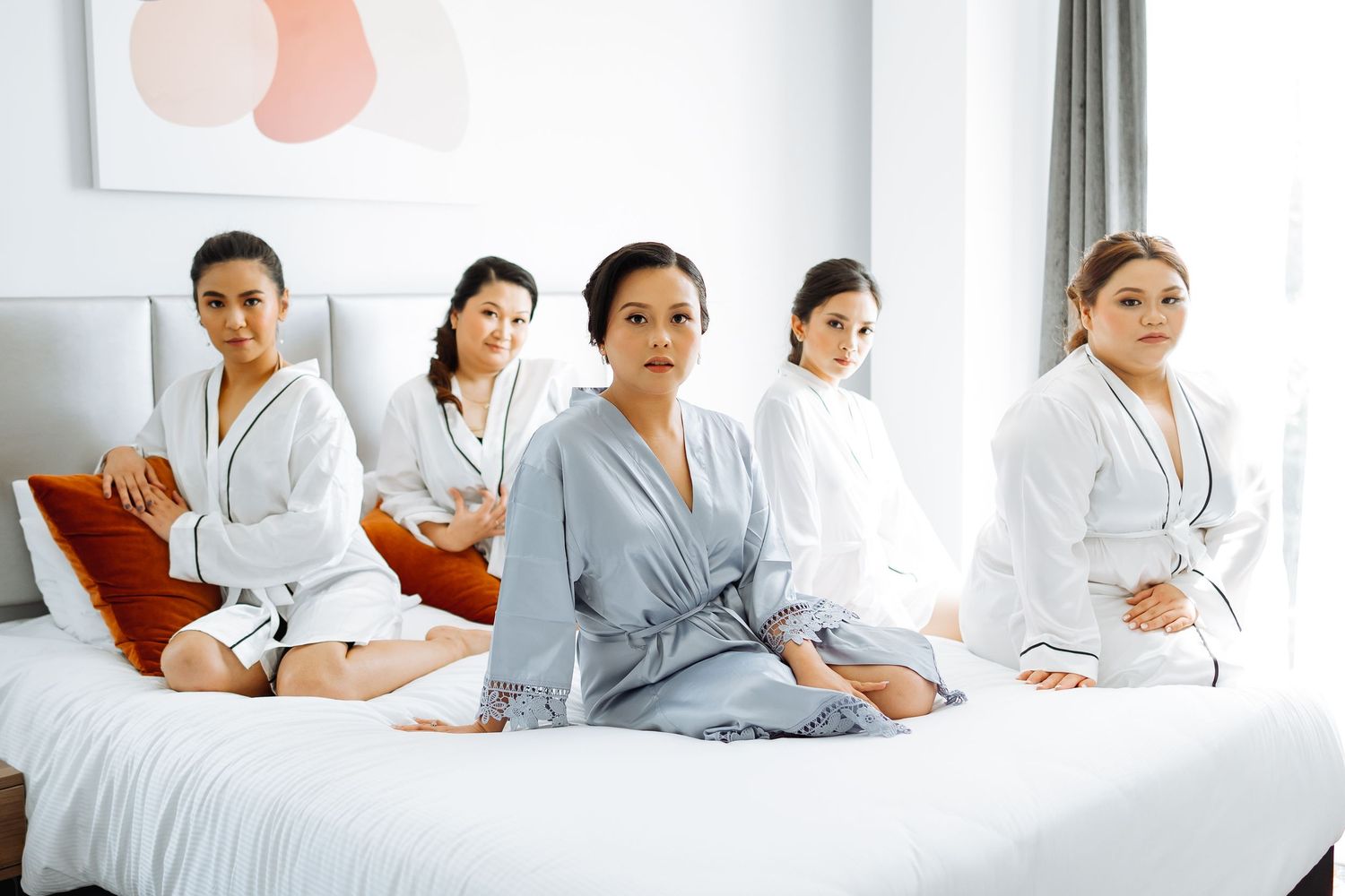 Group portrait in a bright modern room wearing coordinated white and grey outfits.