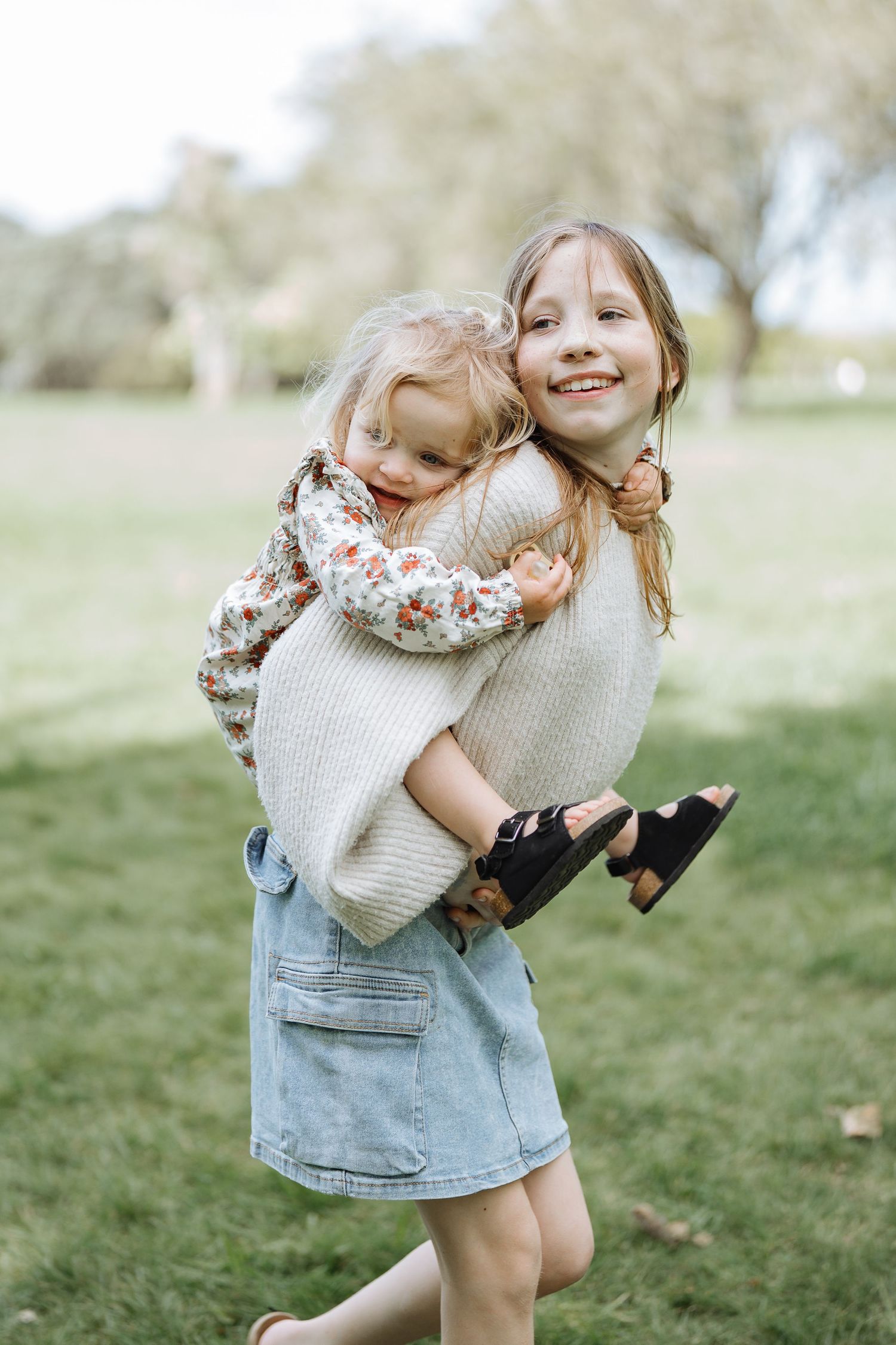 A sweet moment of sisterly bonding with a piggyback ride in a park.