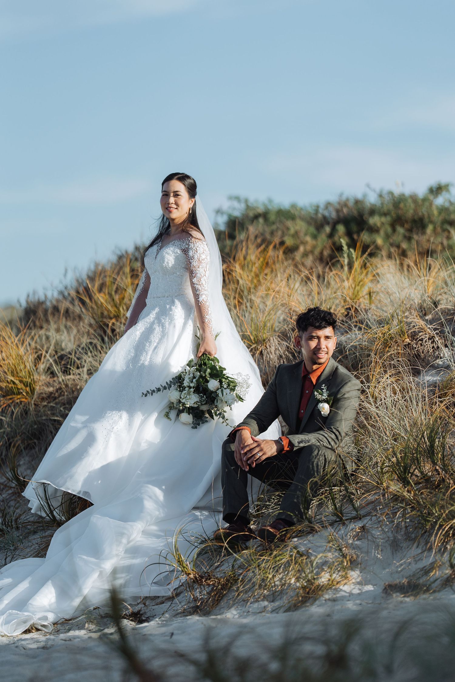 Wedding photo session on sandy dunes with dramatic natural lighting.