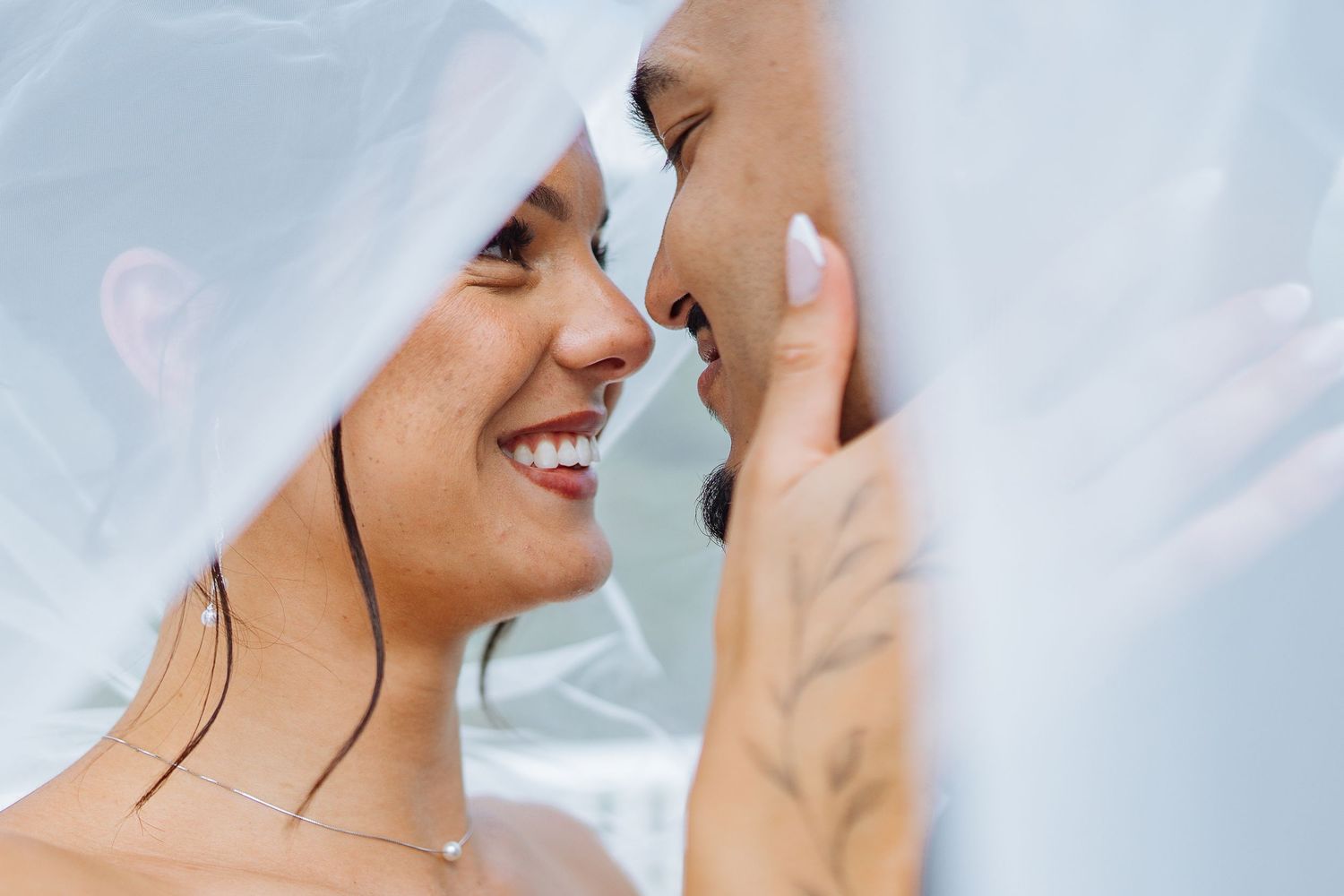 Close-up view of a couple sharing an intimate moment under a white veil.