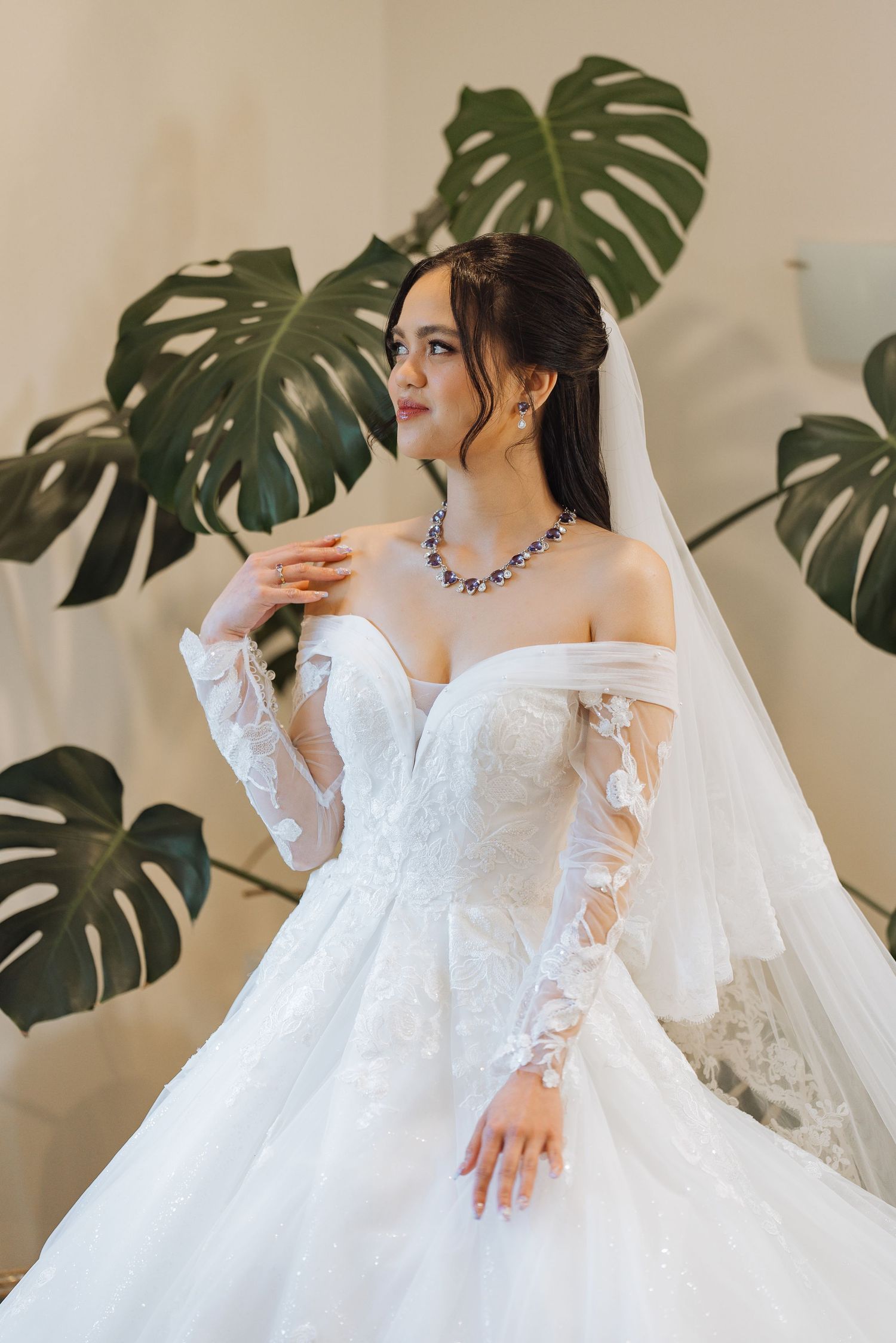 Detailed shots of a white lace wedding gown with monstera leaves in the background.