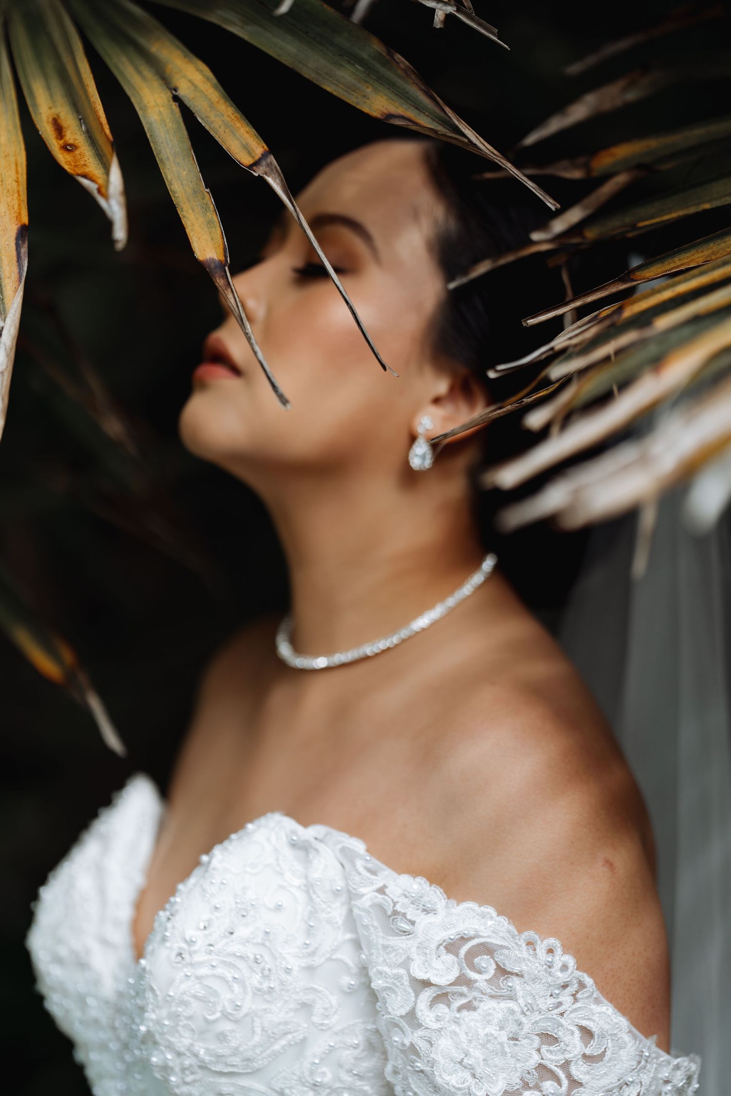 Close-up of bridal details showing pearl necklace and lace dress.