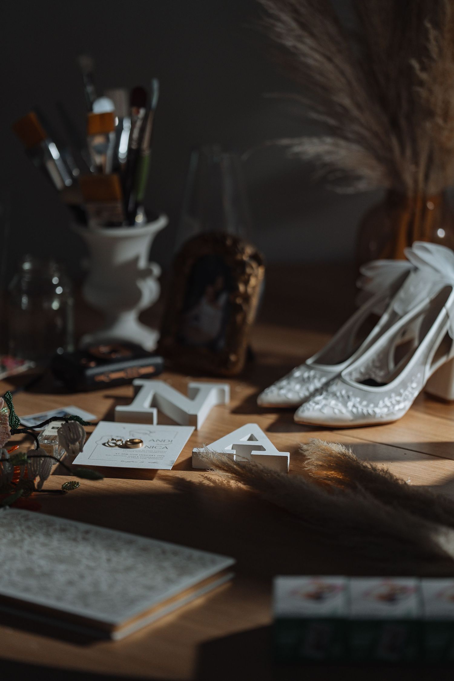 Wedding accessories and details artistically arranged on a dark surface in moody lighting.