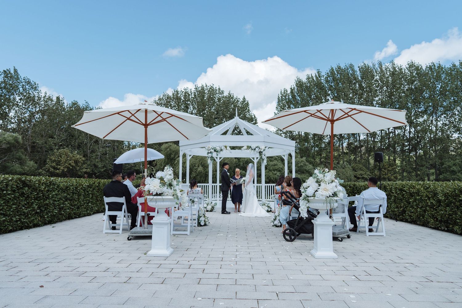 White wedding gazebos arranged outdoors on stone pavement for an elegant ceremony setup.