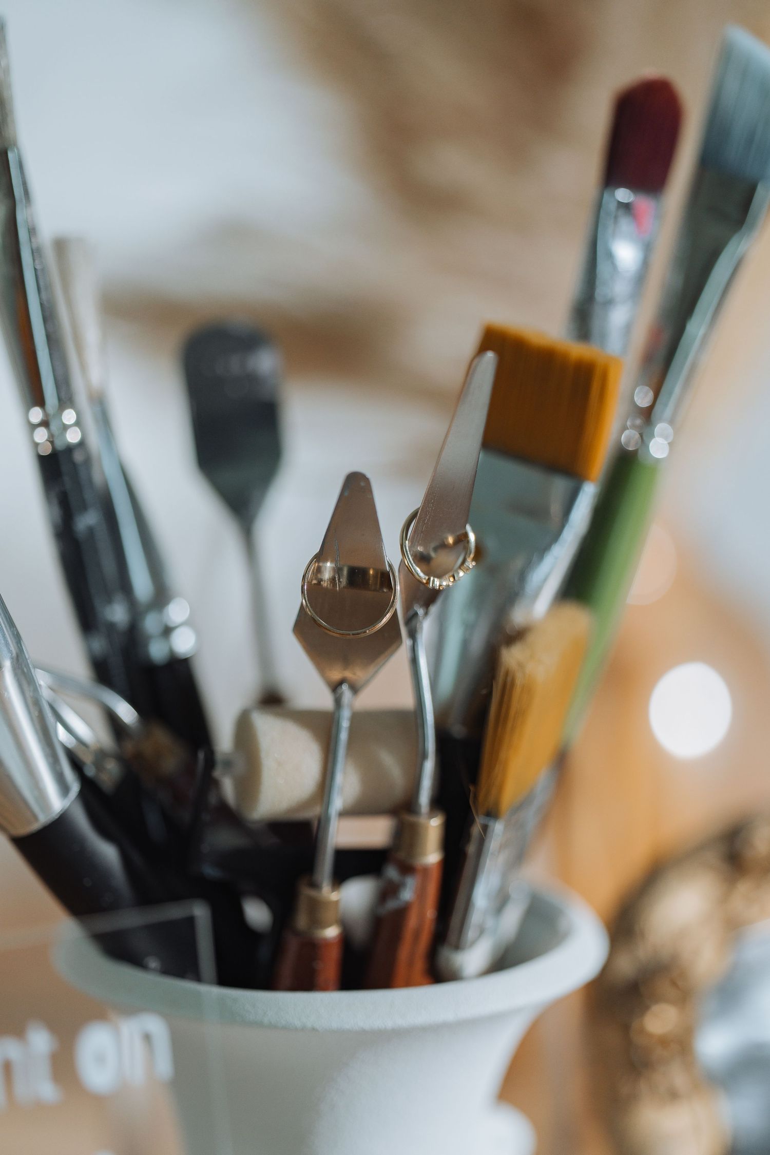 Artistic close-up of paintbrushes and creative tools in a white ceramic holder.