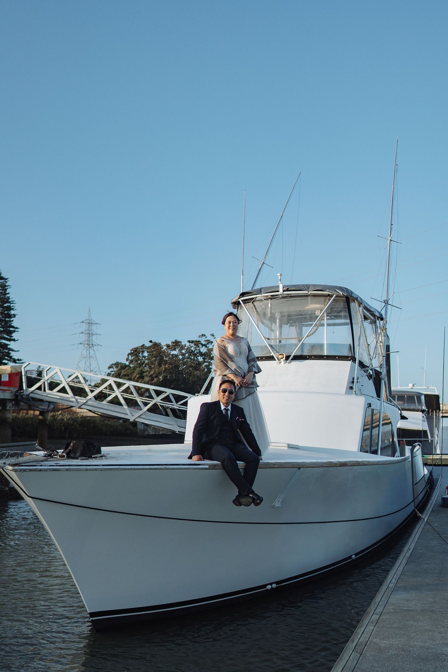 A white yacht moored at a marina dock under clear blue skies.