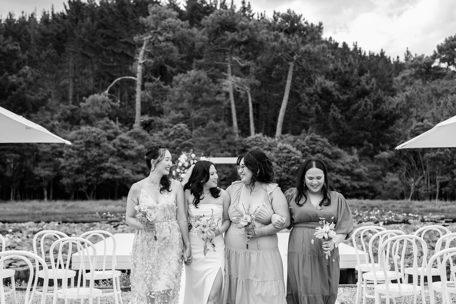 Black and white photo of outdoor wedding setup with white chairs and tent arrangements.