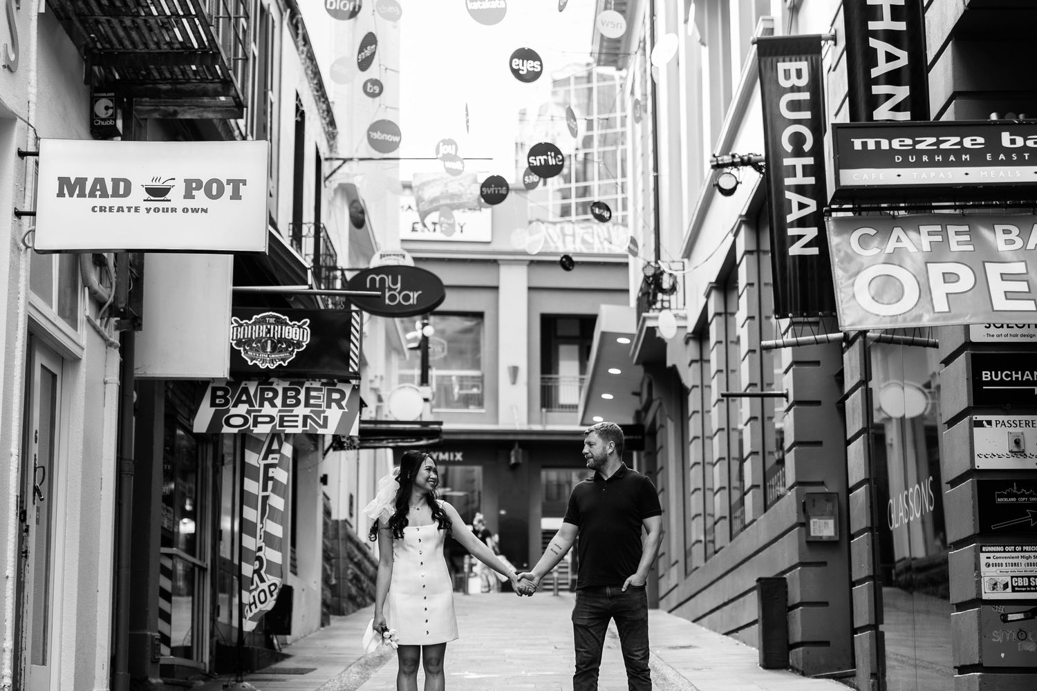 Urban street scene with signs and storefronts in black and white photography.
