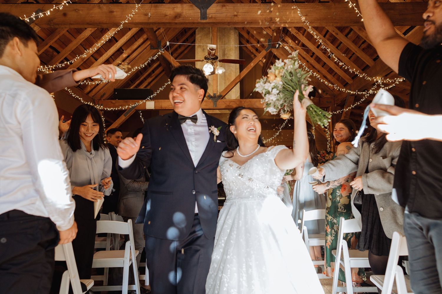 Rustic barn wedding reception with string lights and dancing guests.