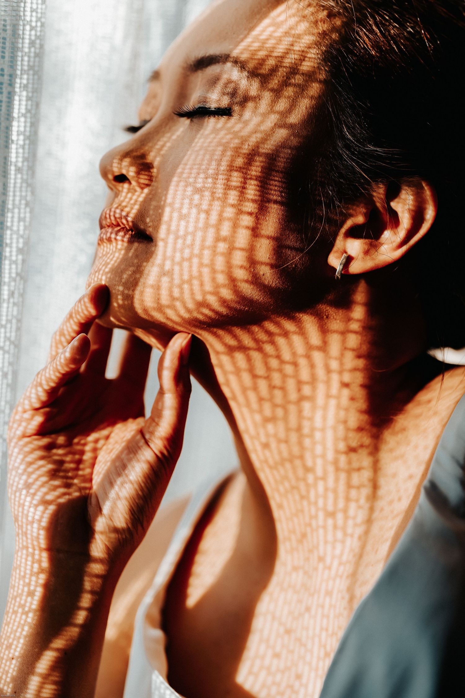 Artistic portrait with dramatic shadows and light patterns creating a textured effect.