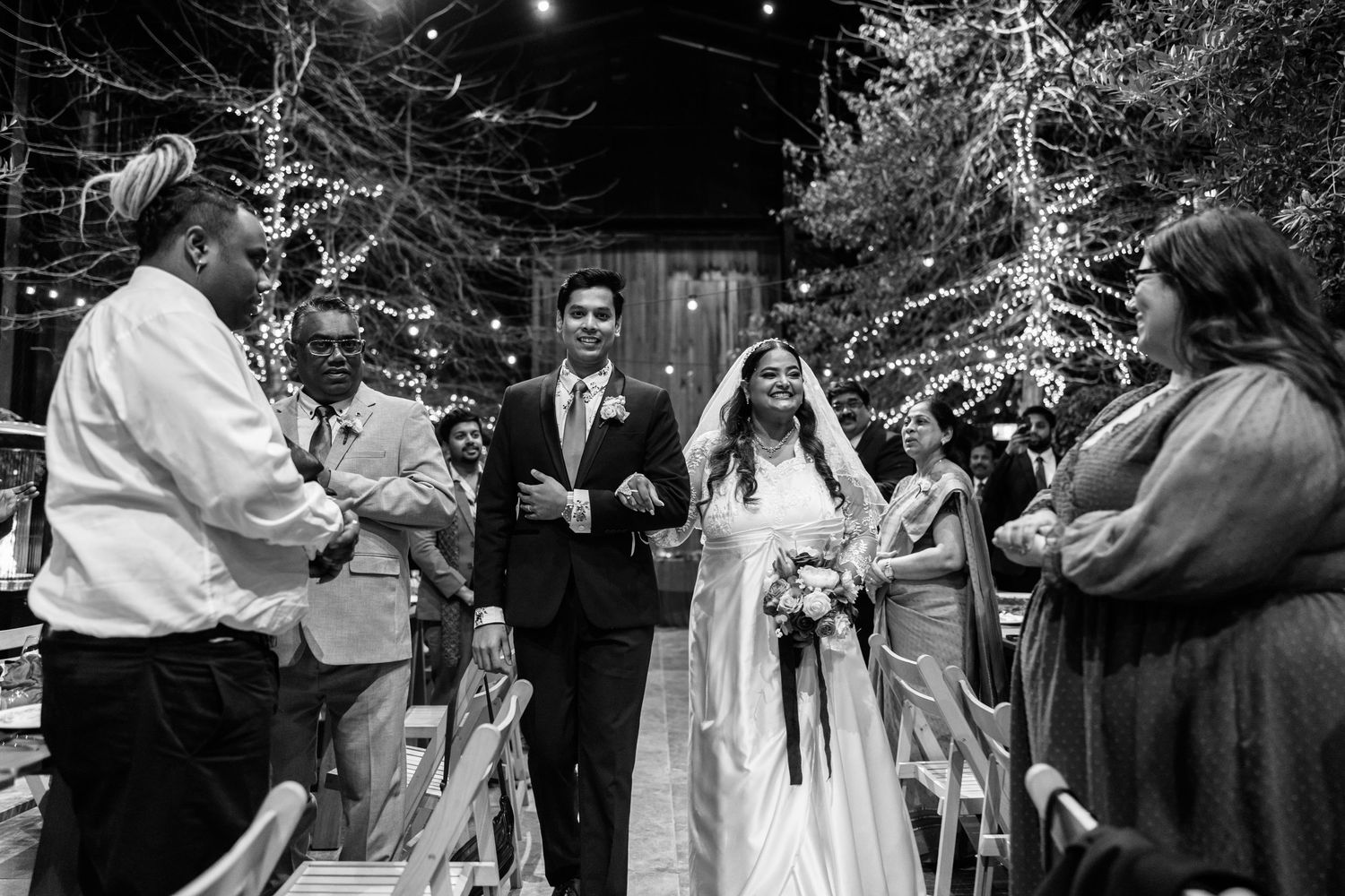 Outdoor nighttime wedding celebration with string lights and dancing guests.