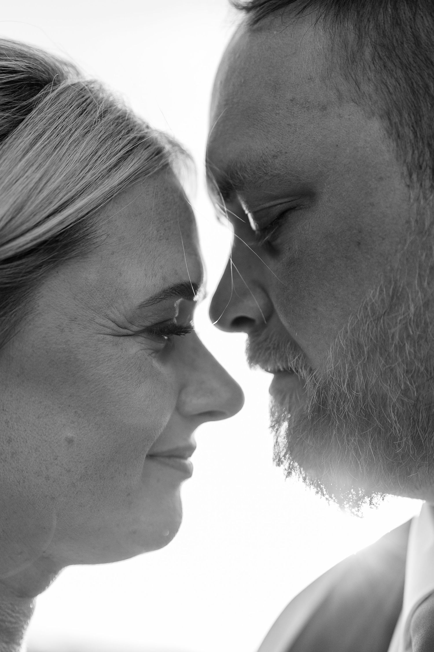 An intimate black and white close-up portrait showing a tender moment between two people.