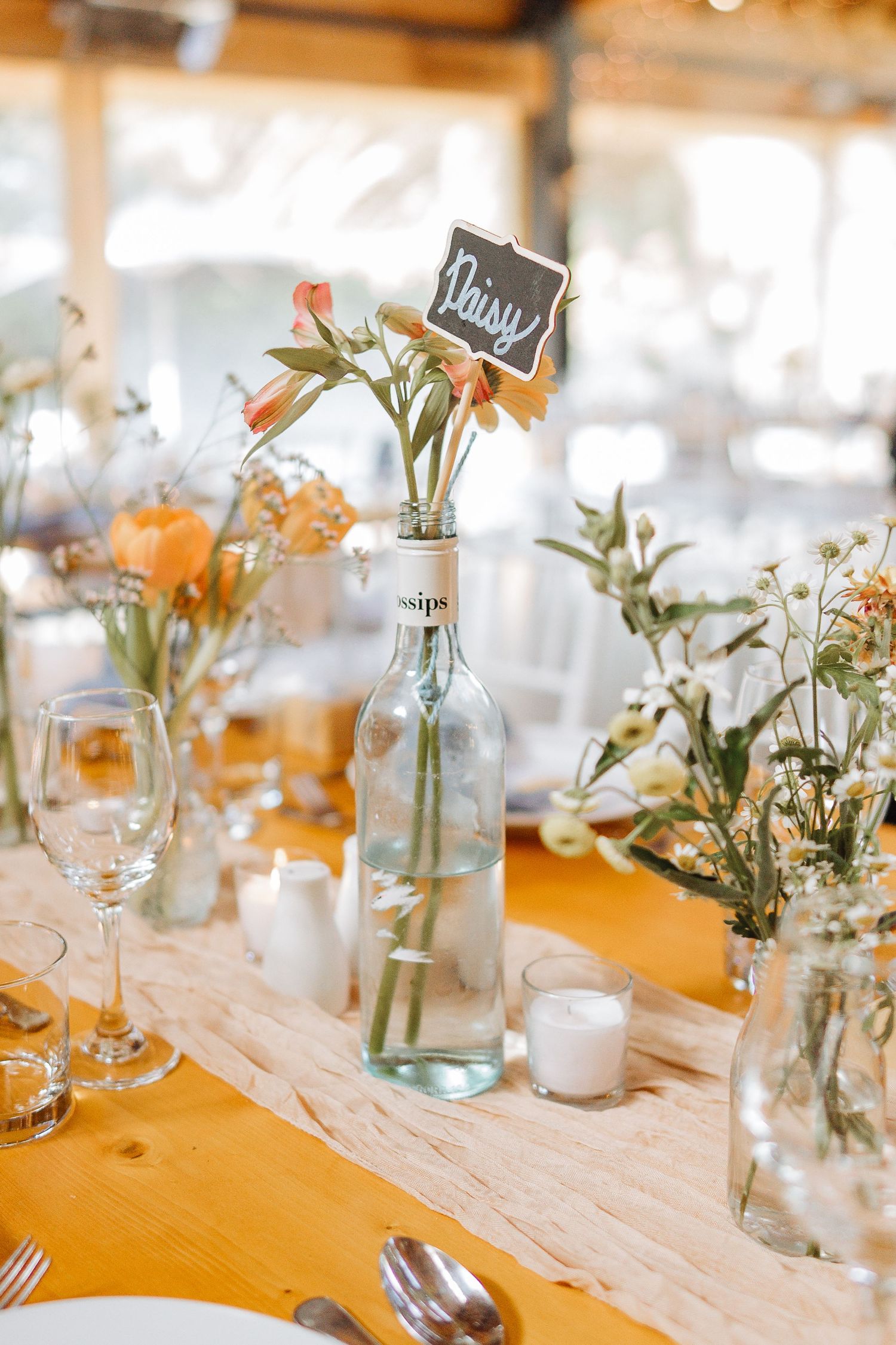 Elegant wedding table decorations with small glass vases holding delicate white flowers and greenery.