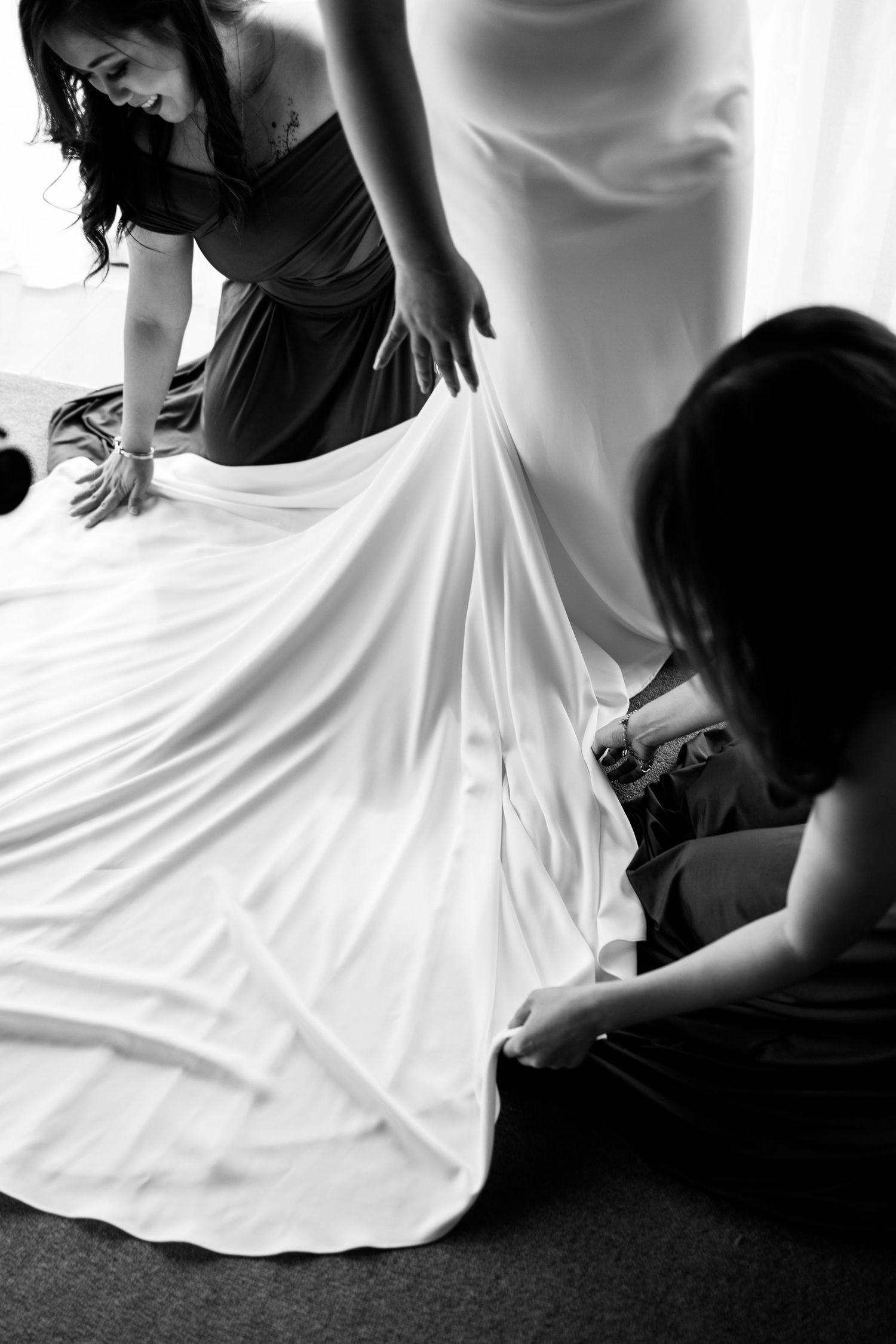 Black and white photo of wedding dress being adjusted before ceremony.