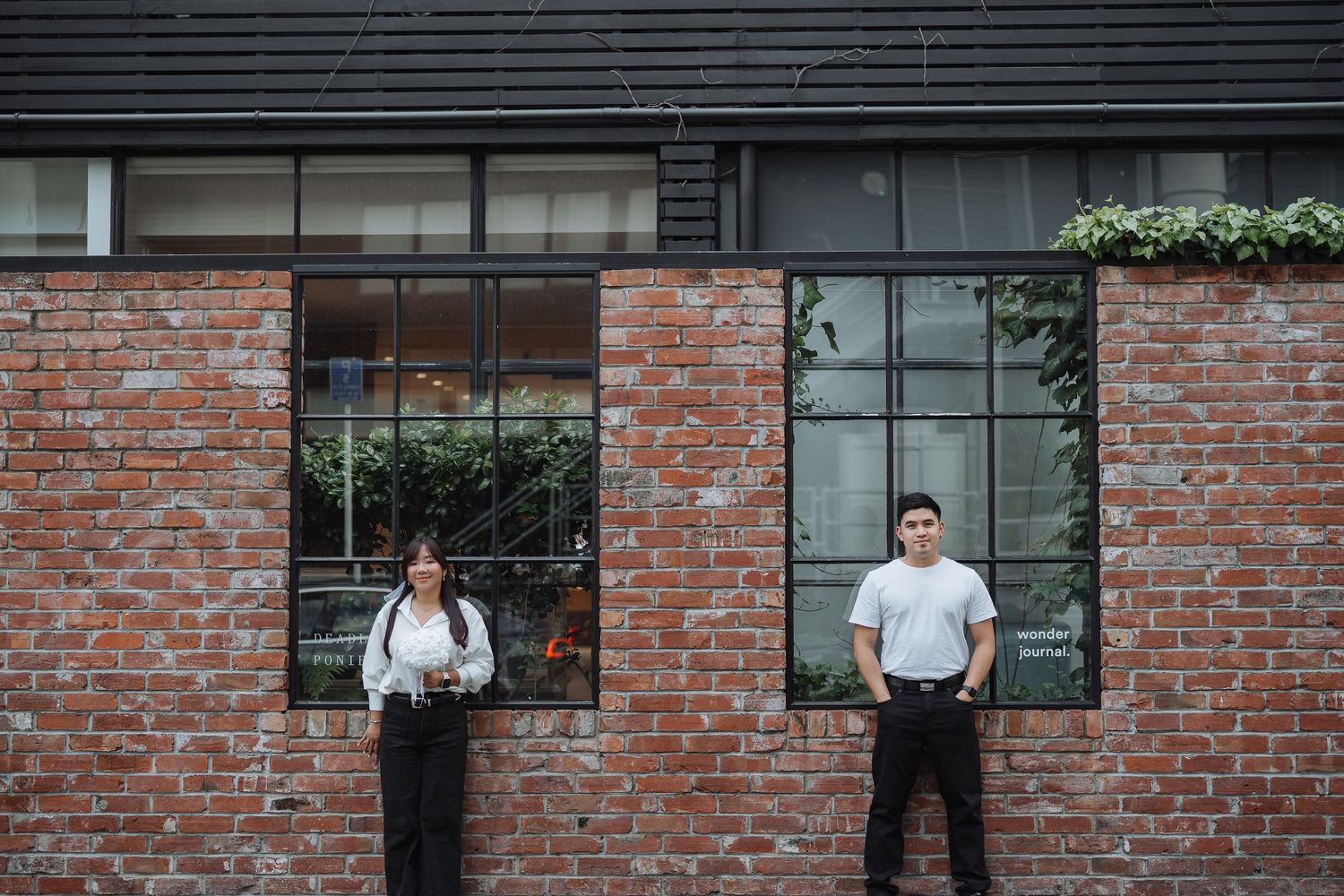 People standing against a brick wall backdrop in an industrial setting.