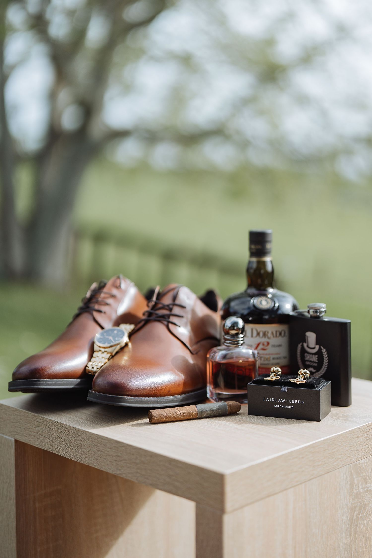 Brown leather dress shoes and cologne bottles arranged on wooden display blocks.