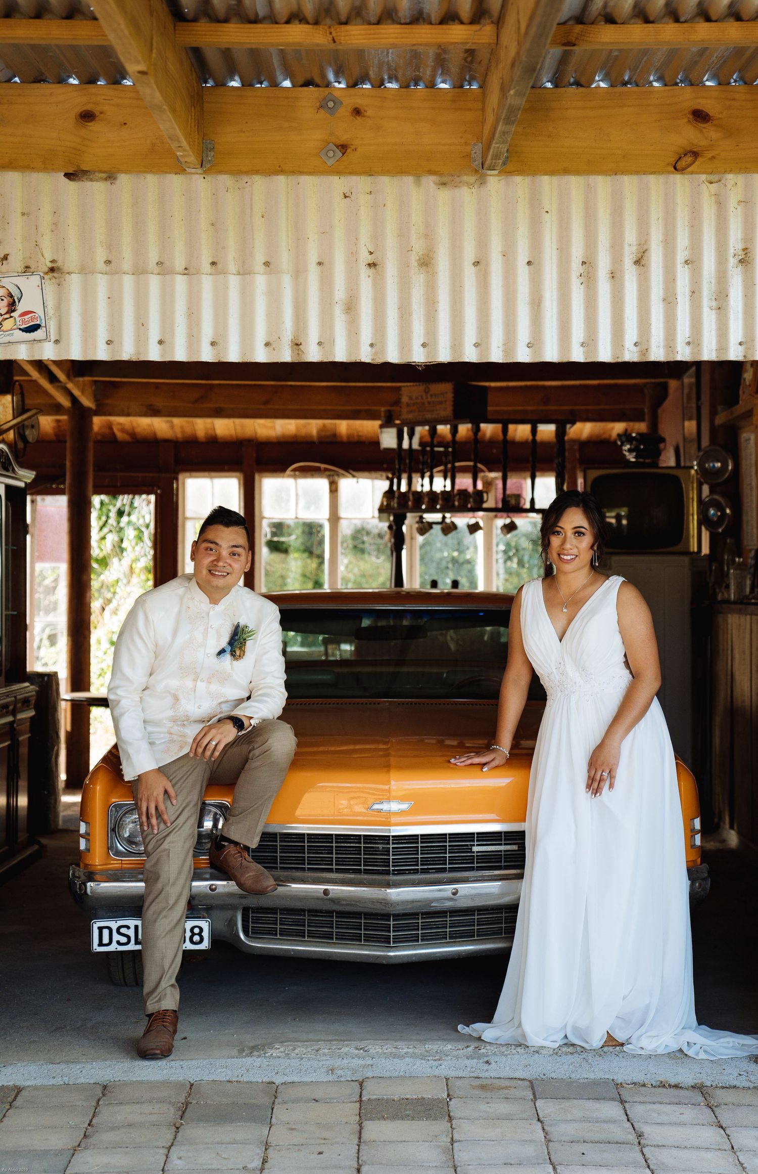 Rustic venue setting with wooden beams and vintage car in background.