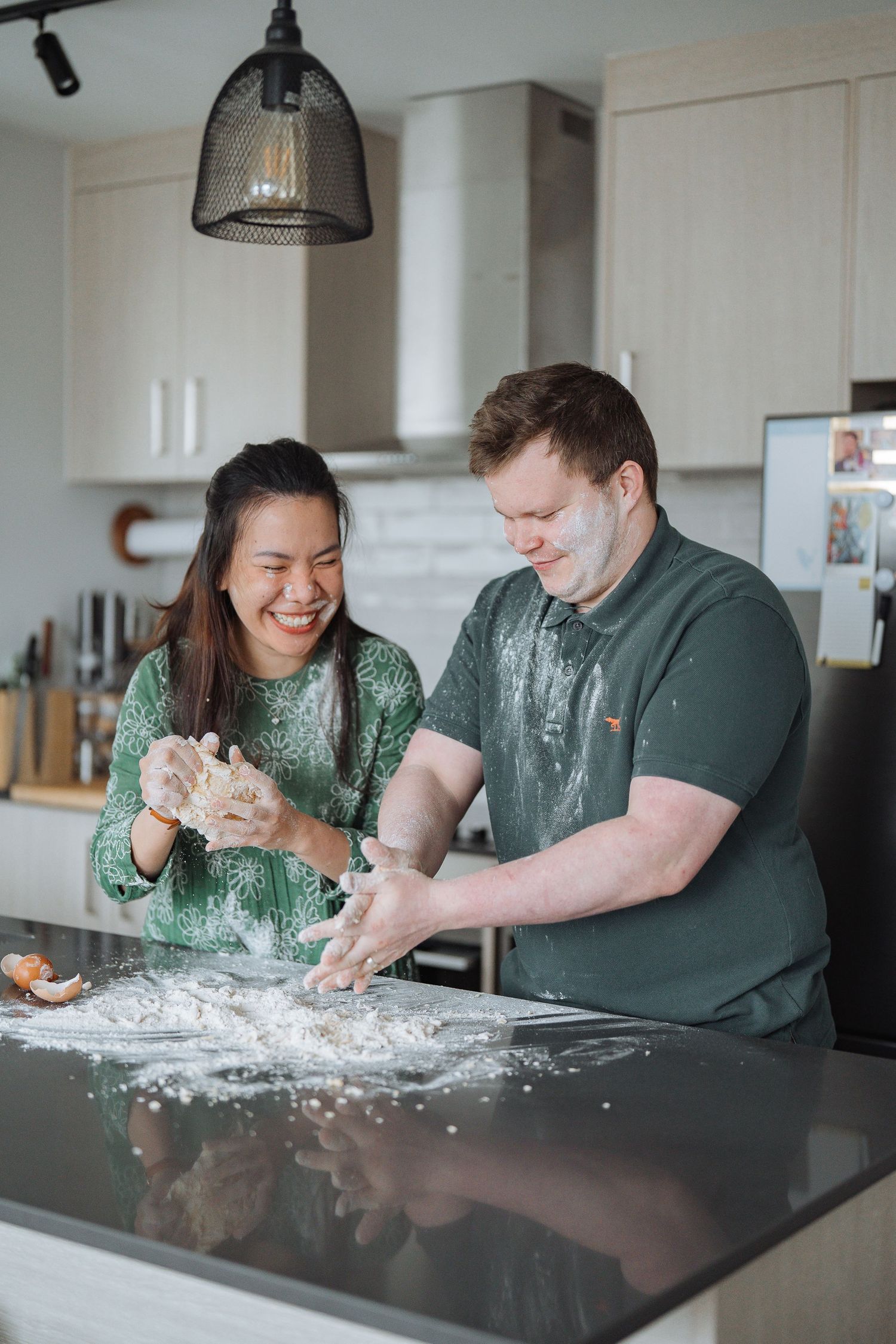 A couple plays with flour while baking together at a kitchen counter.
