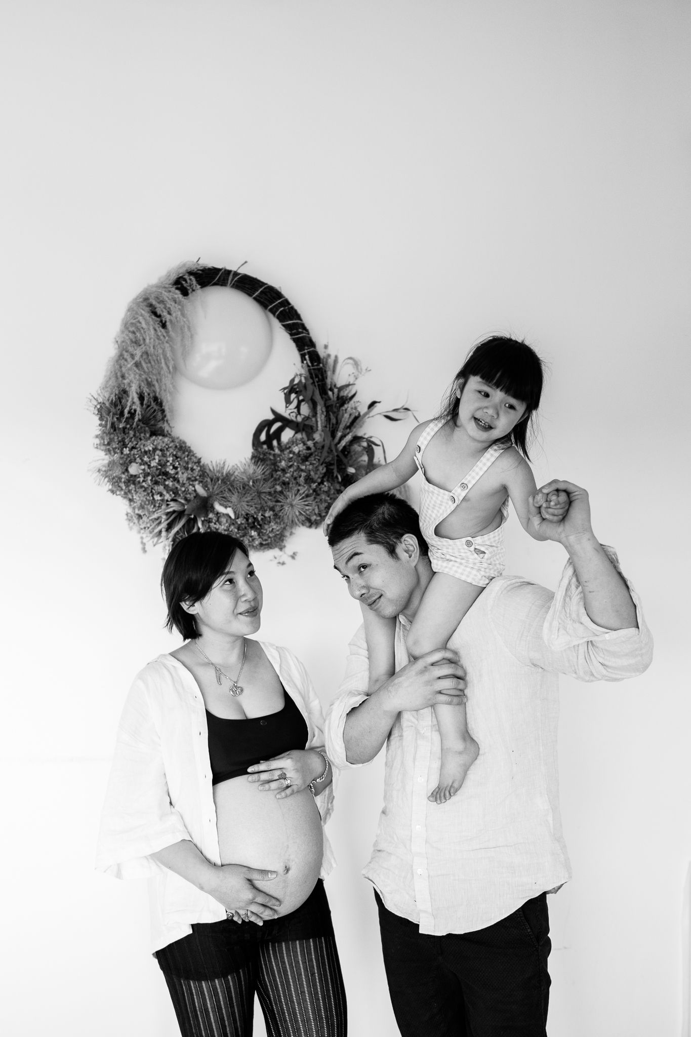 Black and white artistic family portraits showing playful poses against a white backdrop.