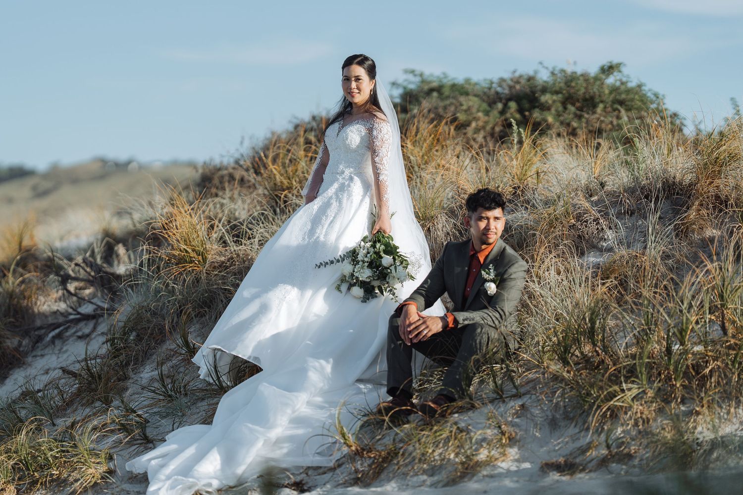 A wedding couple poses dramatically against a desert landscape with golden light.