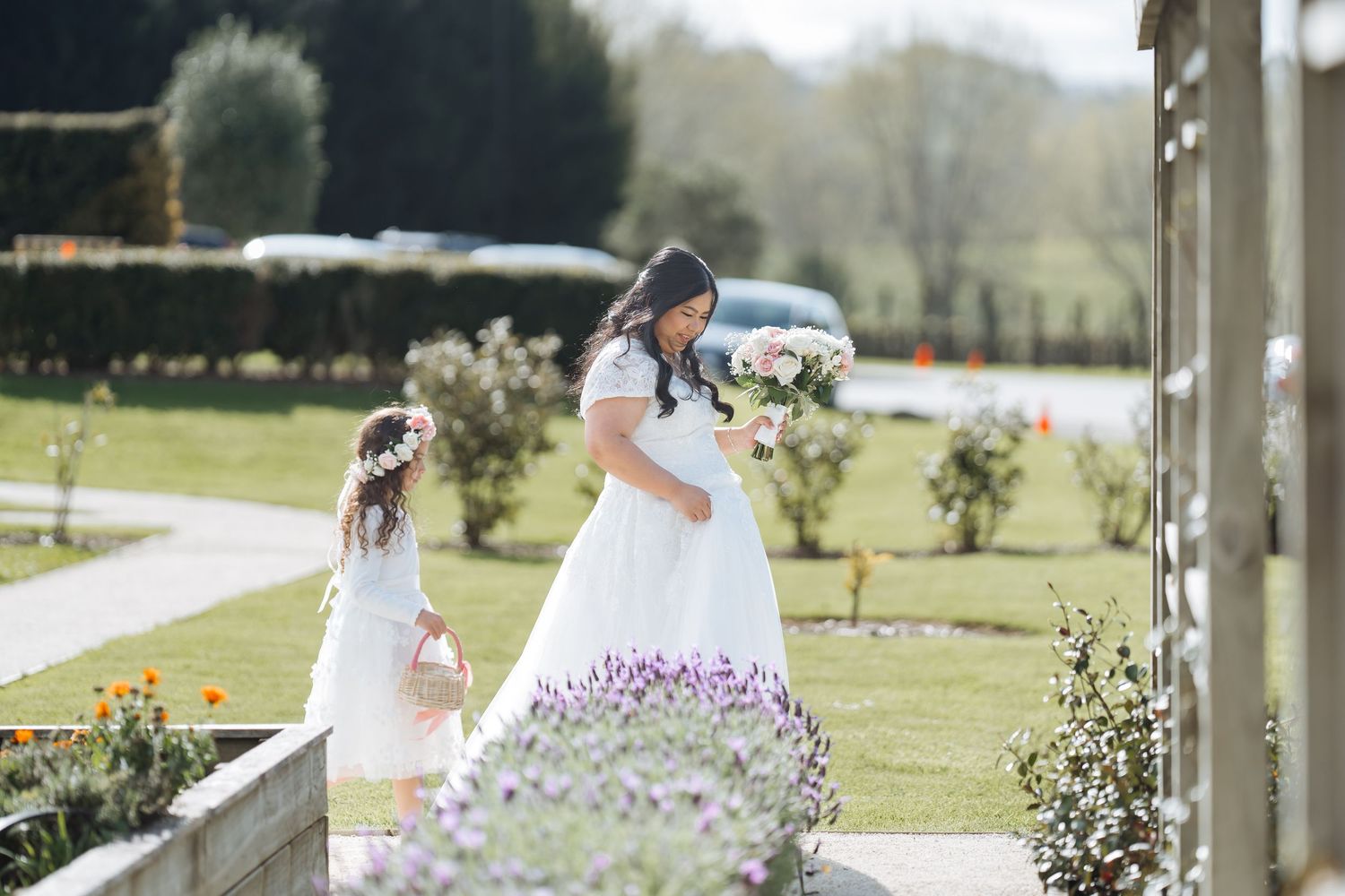 Wedding couple walking through a sunny garden path with spring flowers.