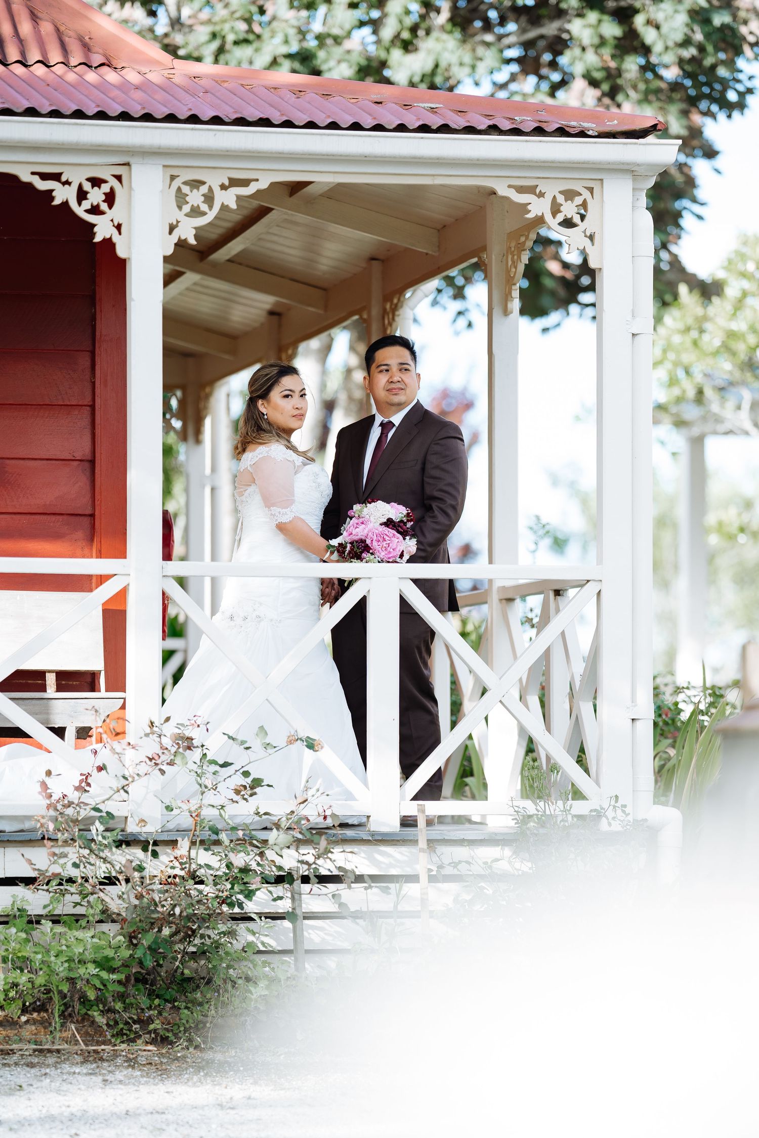 Romantic wedding portrait session on a white porch of a red farmhouse.