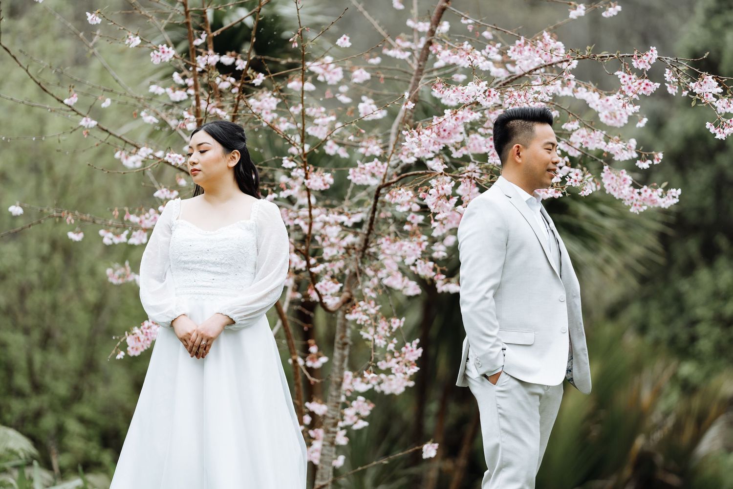 Romantic wedding portrait among blooming cherry blossom trees in springtime.