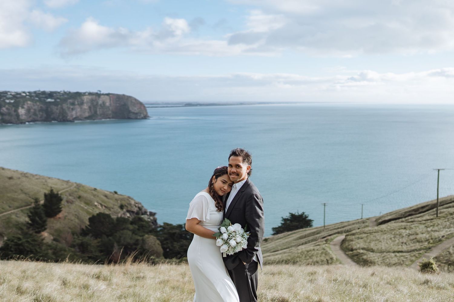 A scenic coastal wedding ceremony with dramatic cliffs and ocean views in the background.