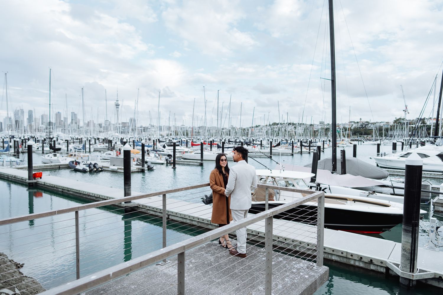 Marina dock with boats and yachts lined up under cloudy skies.