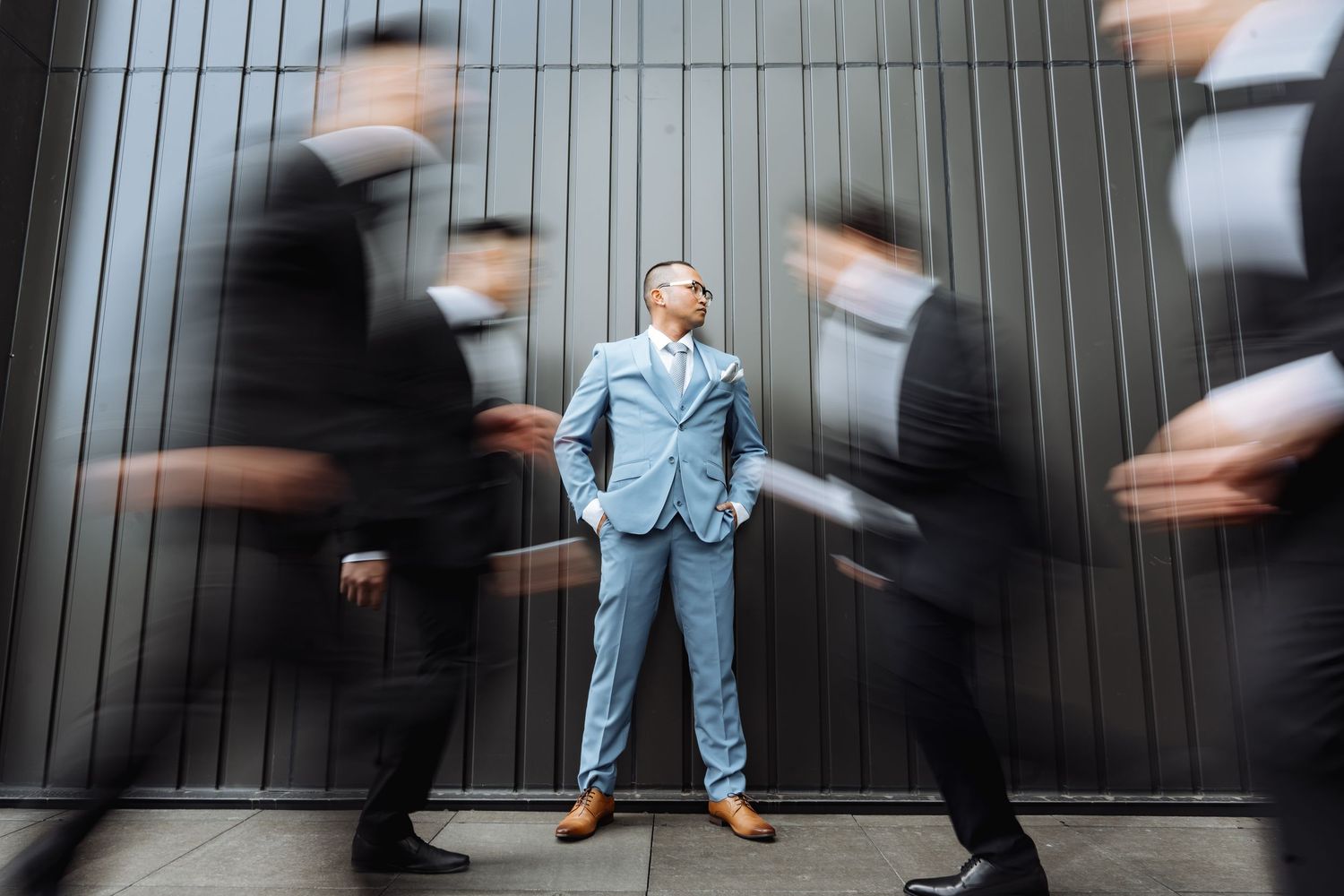 Time-lapse sequence showing motion blur around a still figure in a light suit against dark walls.
