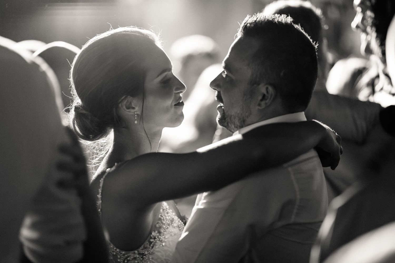 A romantic black and white silhouette of a couple sharing an intimate moment during their wedding celebration.