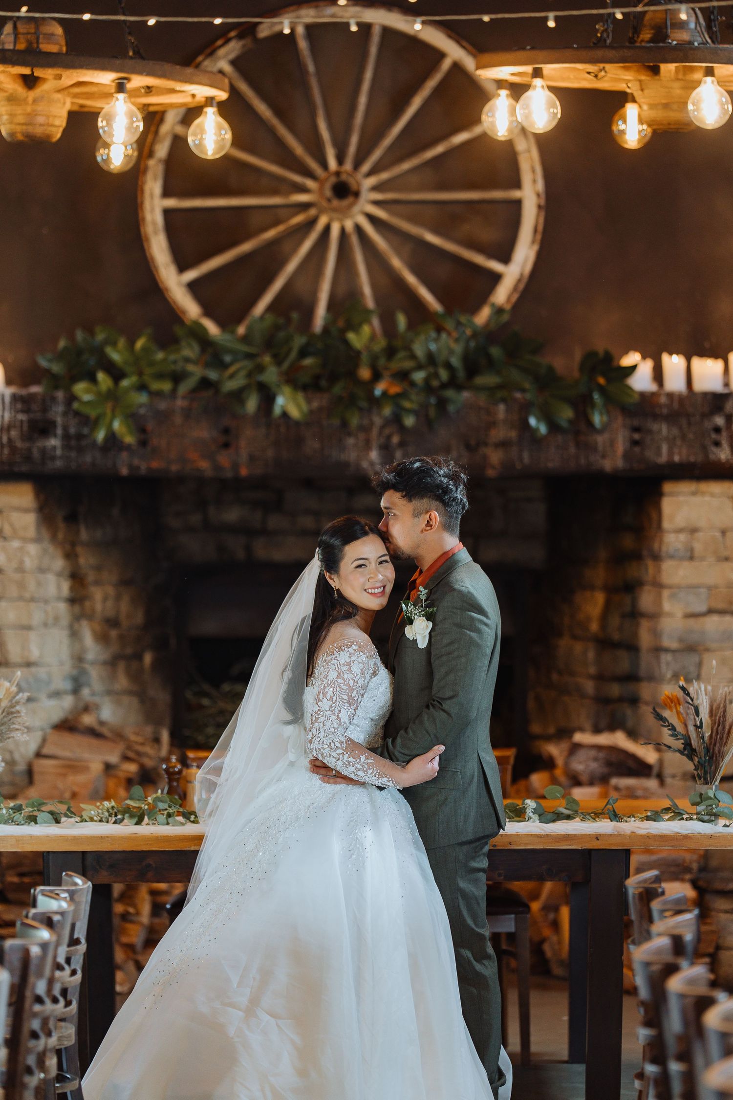 Rustic wedding venue decorated with wagon wheel and string lights creating romantic ambiance.