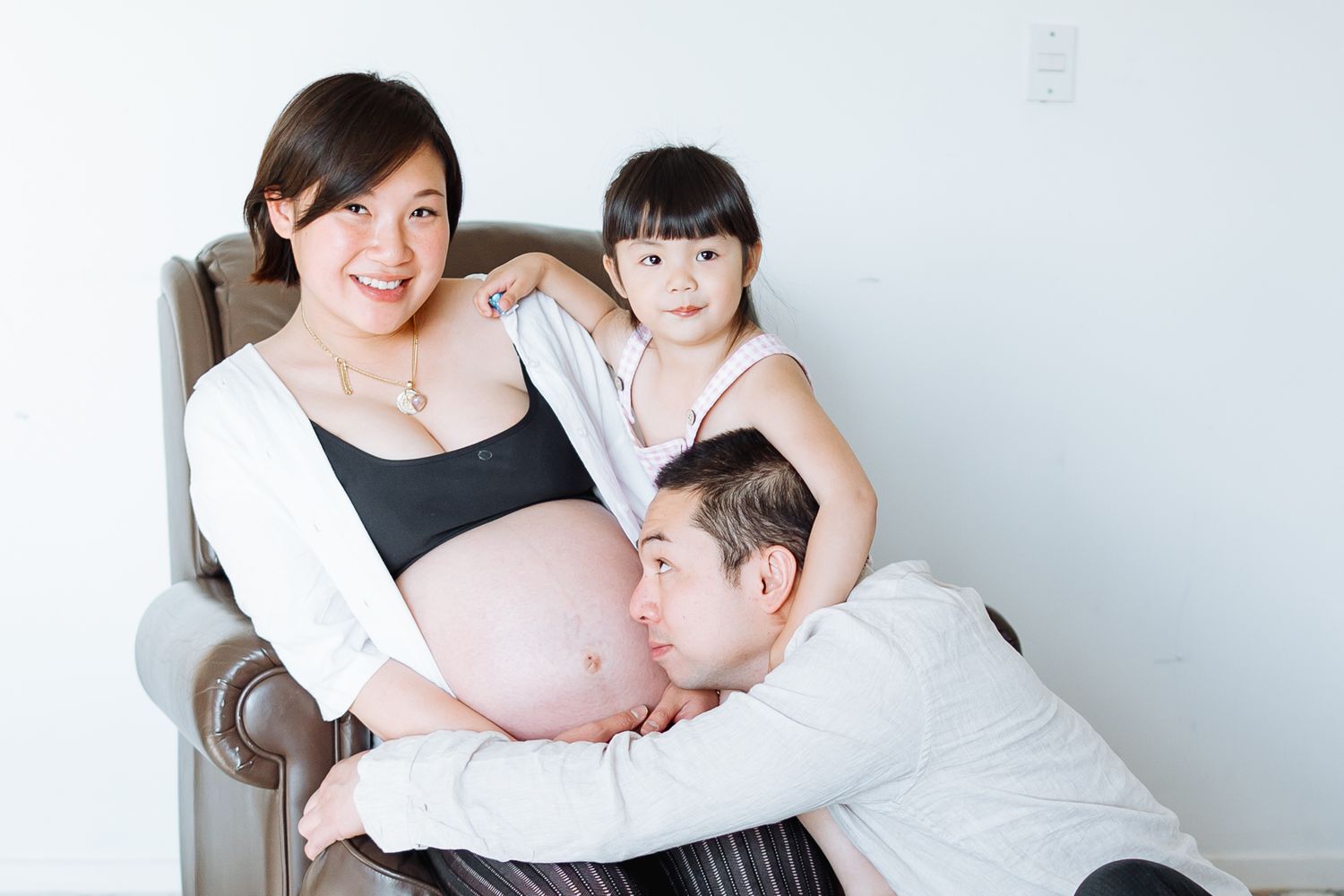 A maternity photo session showing tender family moments against a white background.