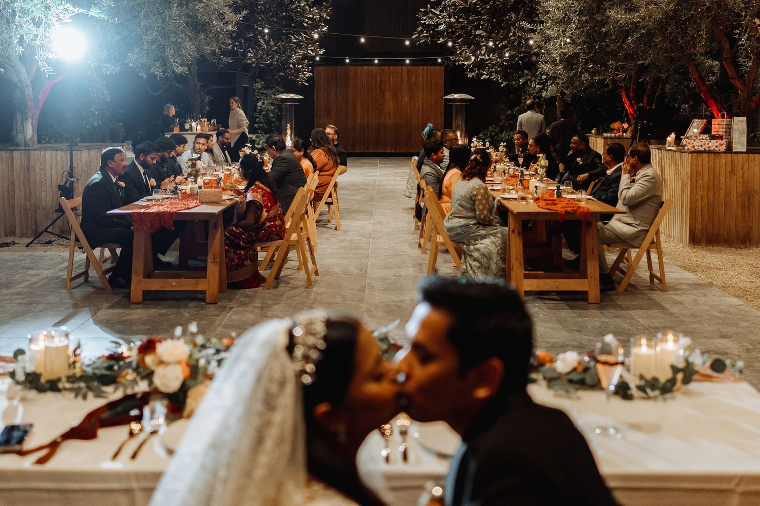 Wedding reception venue with rustic wooden tables and ambient lighting.
