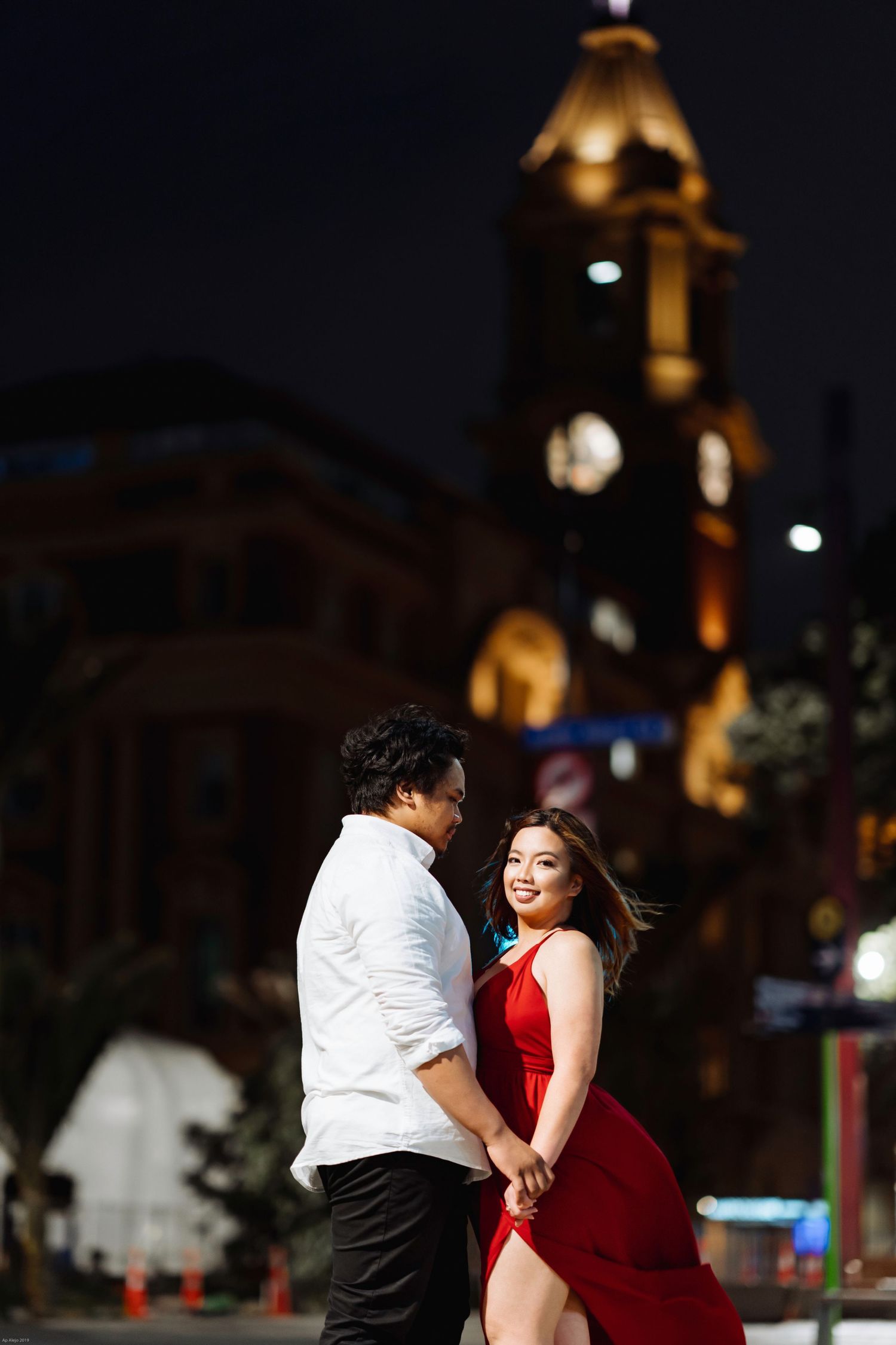 Romantic nighttime photoshoot with illuminated historic buildings in background.