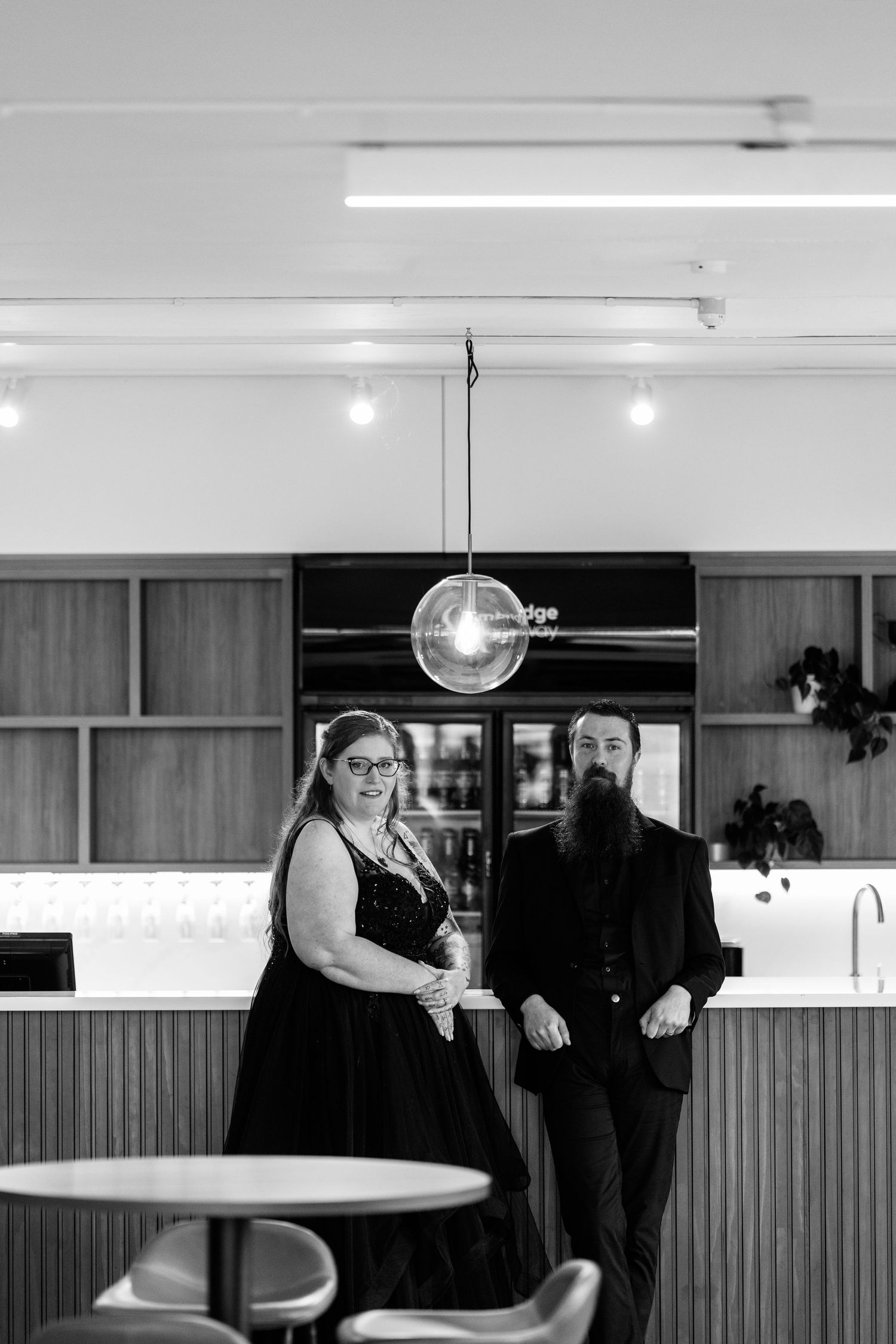 Black and white photograph of people in formal wear at a retro-style diner counter.