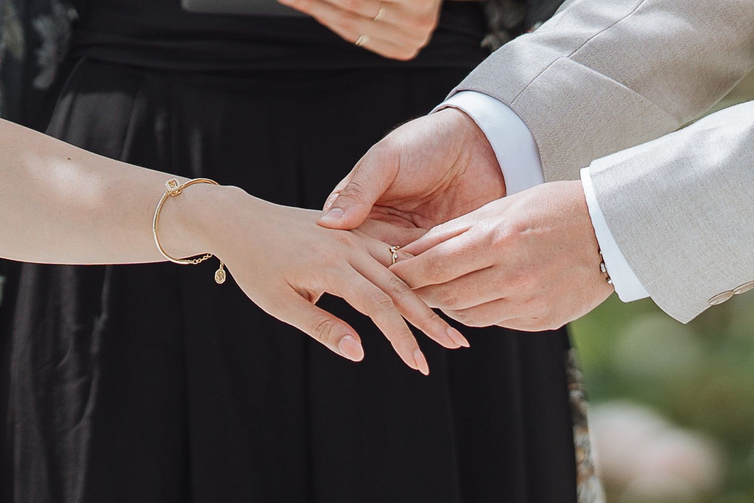 Close-up shot of hands exchanging rings during a wedding ceremony.