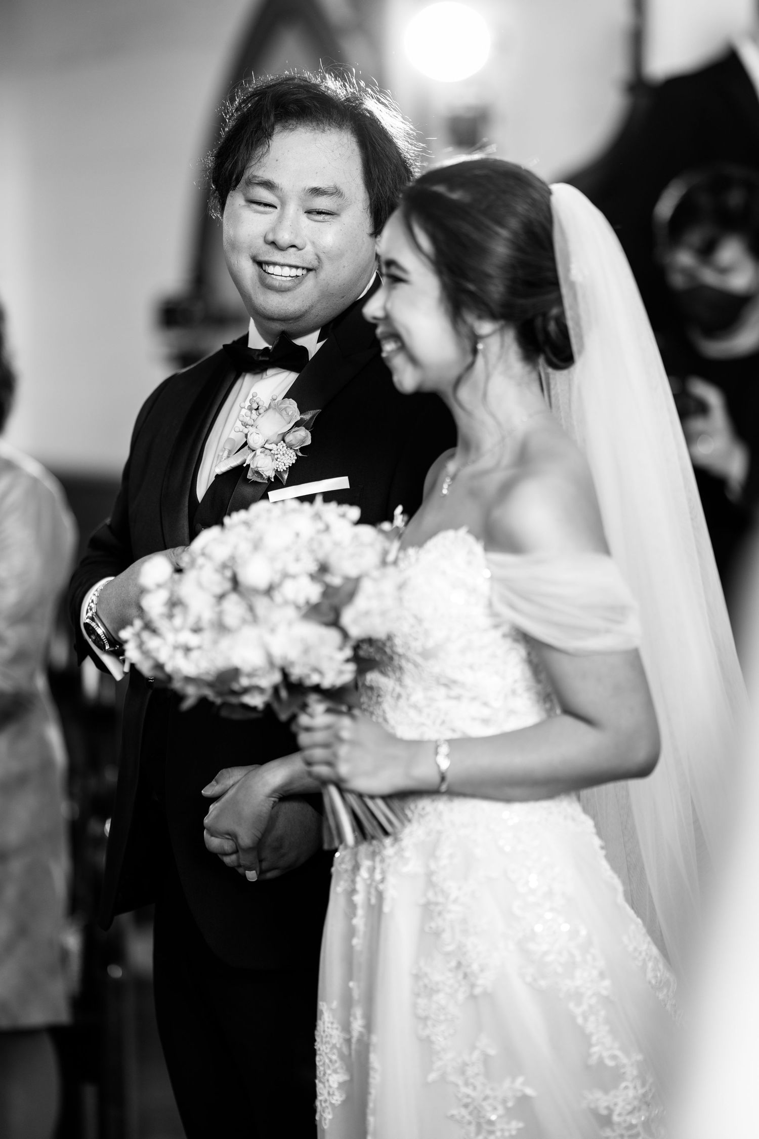 A black and white wedding portrait capturing a tender moment with a bouquet.