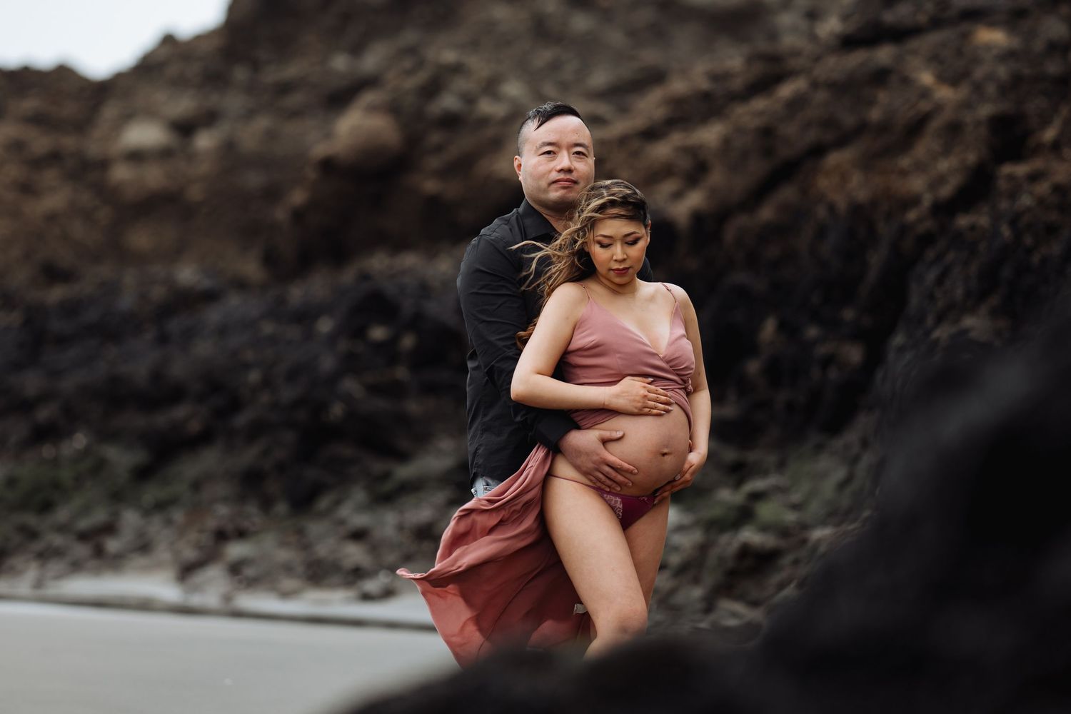 A tender moment captured between a couple against rugged coastal cliffs.