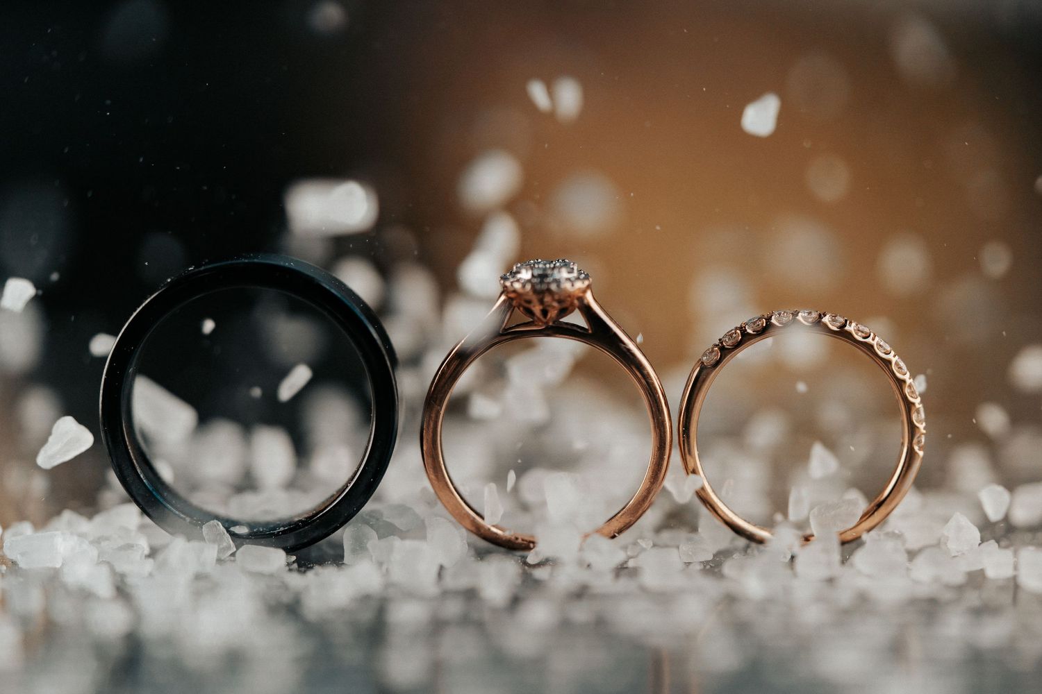 Wedding rings displayed artistically with bokeh lights and sparkles in the background.