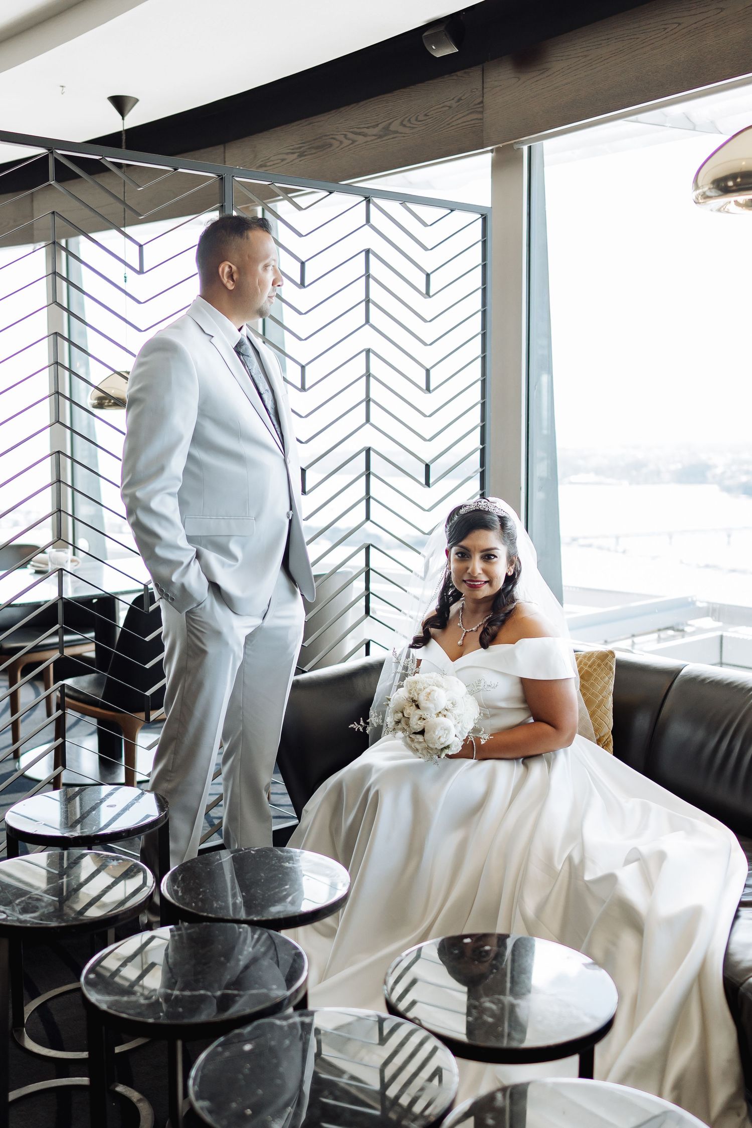 Wedding photo in modern restaurant with geometric wall pattern and city views.