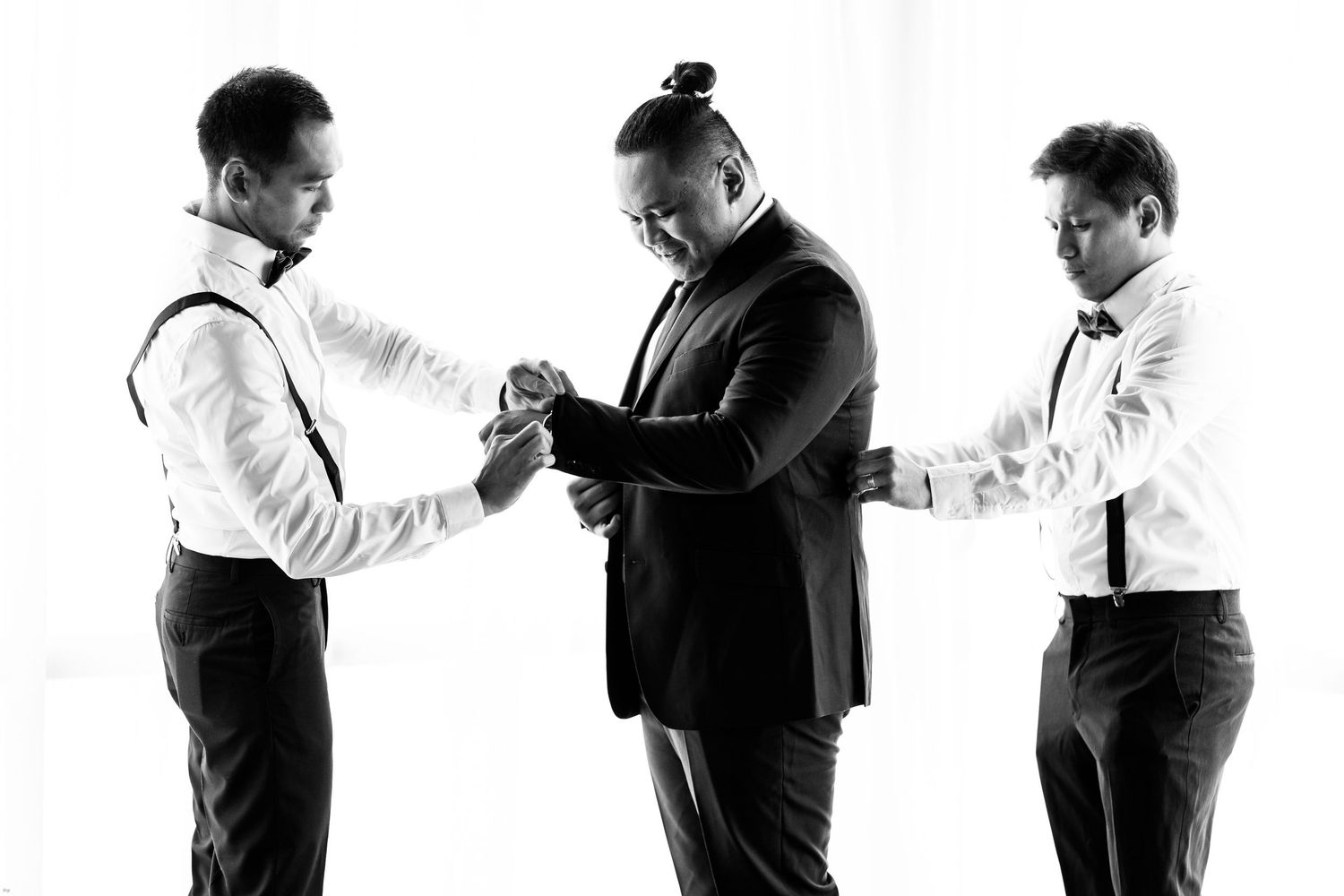 Black and white sequence of groomsmen adjusting ties and preparing for ceremony.