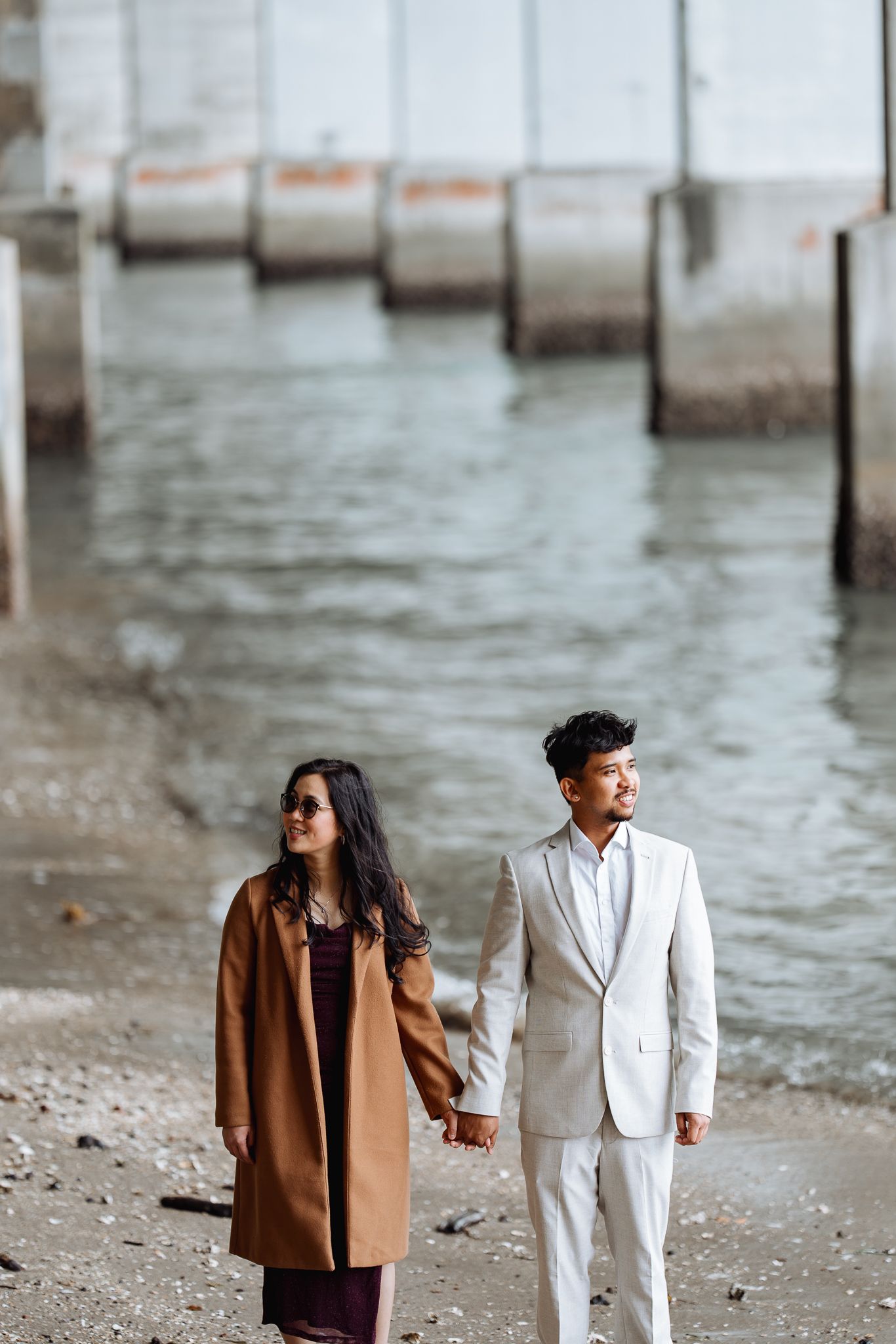 Couple in contrasting outfits walking along waterfront.