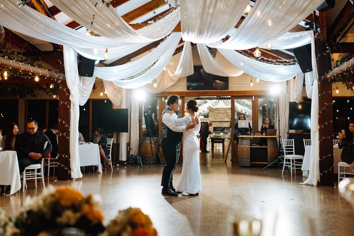 Wedding reception venue decorated with elegant white draping and string lights.