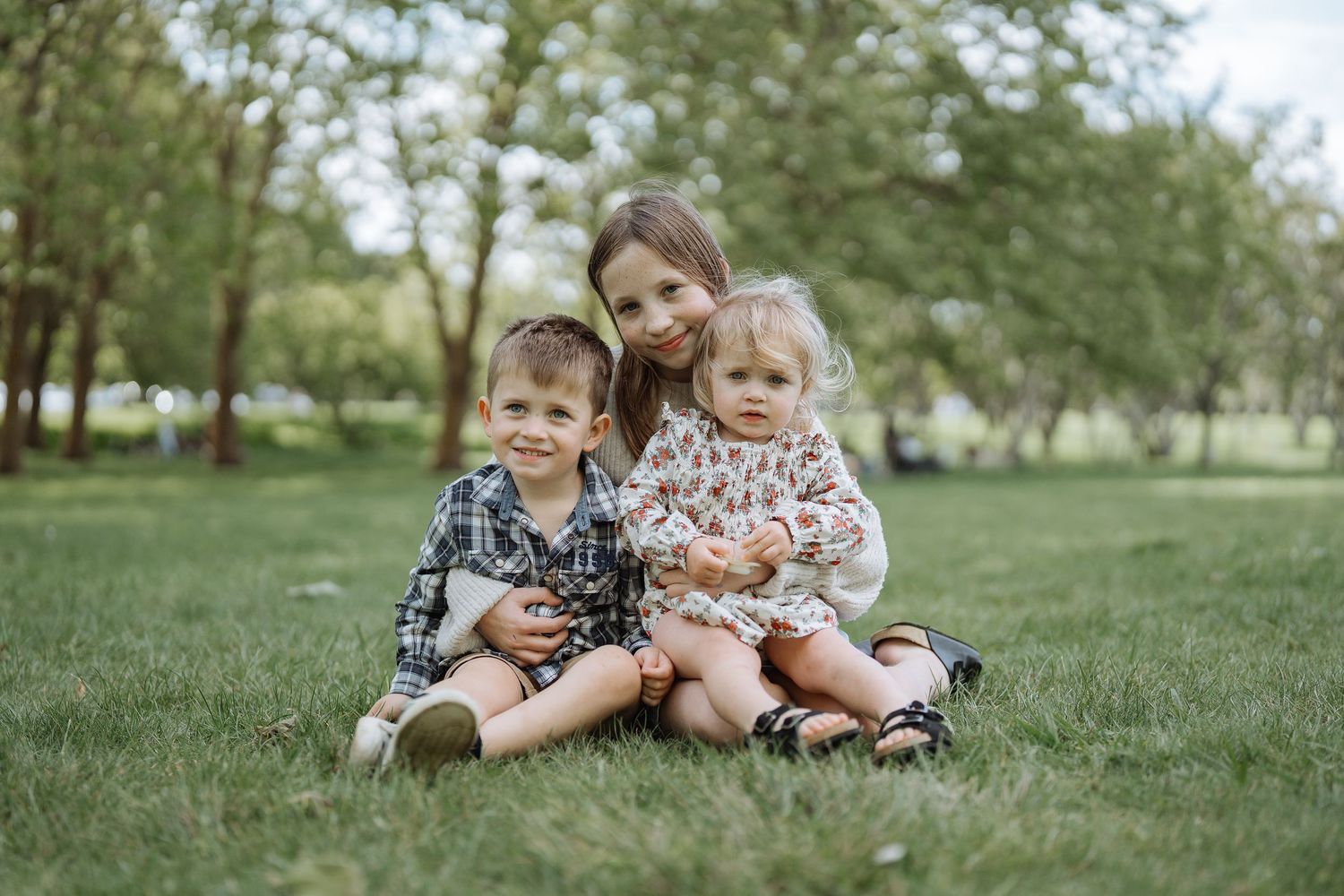 Family enjoying a playful moment together on green grass in a park setting.